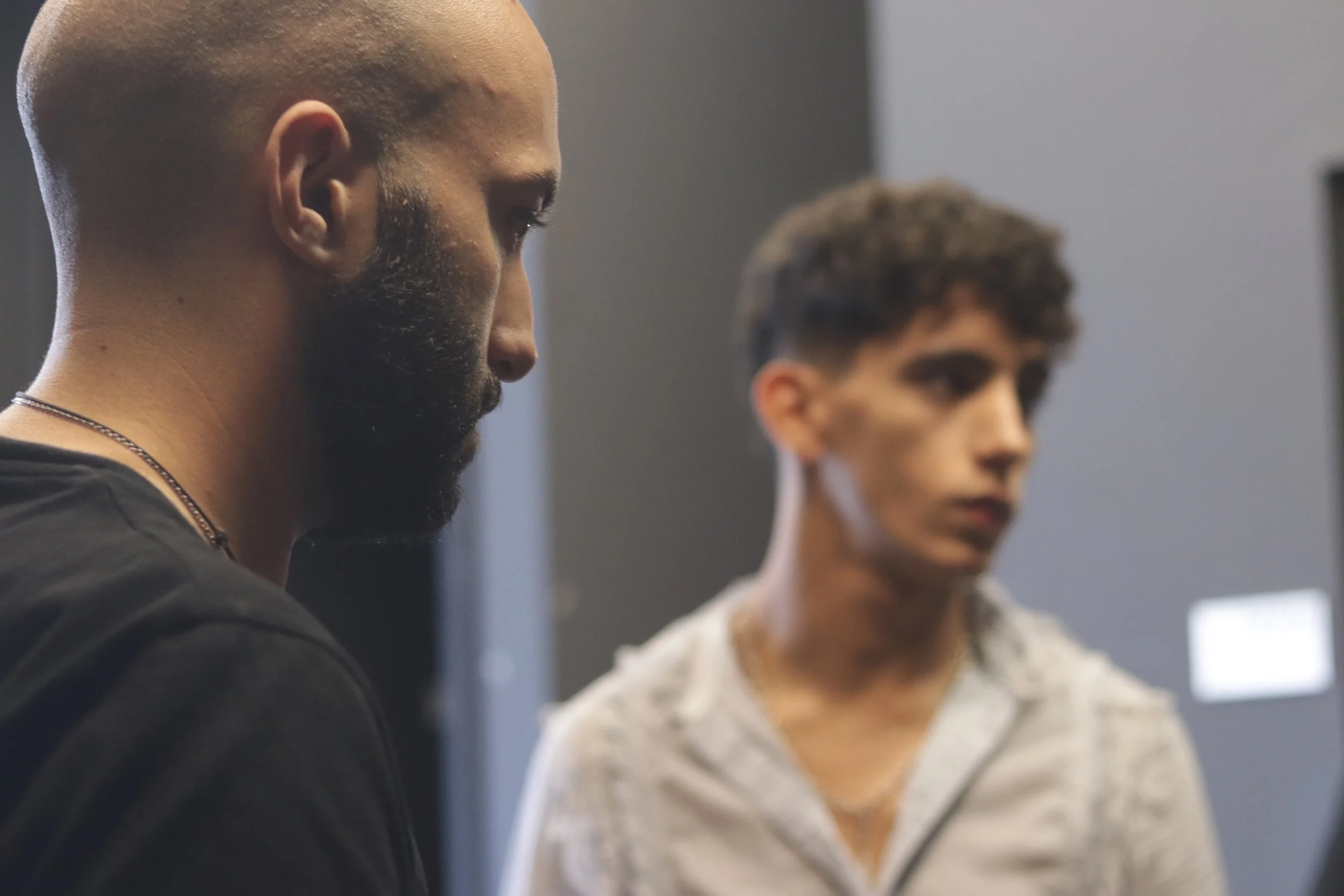 Dos hombres en un interior con fondo borroso.