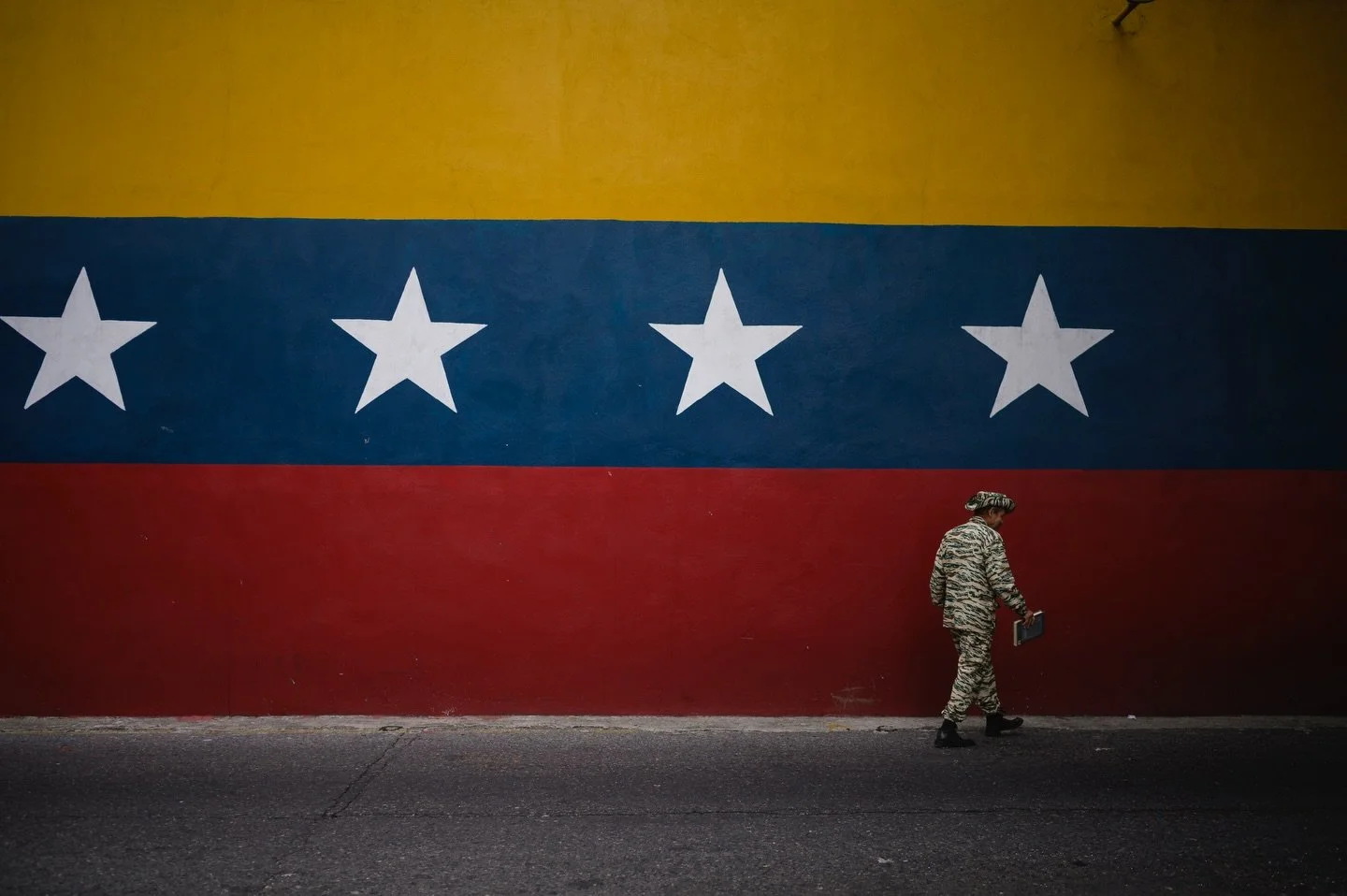 A member of the Bolivarian Militia walks past a mural of the Venezuelan flag amid rising tensions between the administration of U.S. President Donald Trump and the government of Venezuela&rsquo;s President Nicolas Maduro, in Caracas, Venezuela, Novem