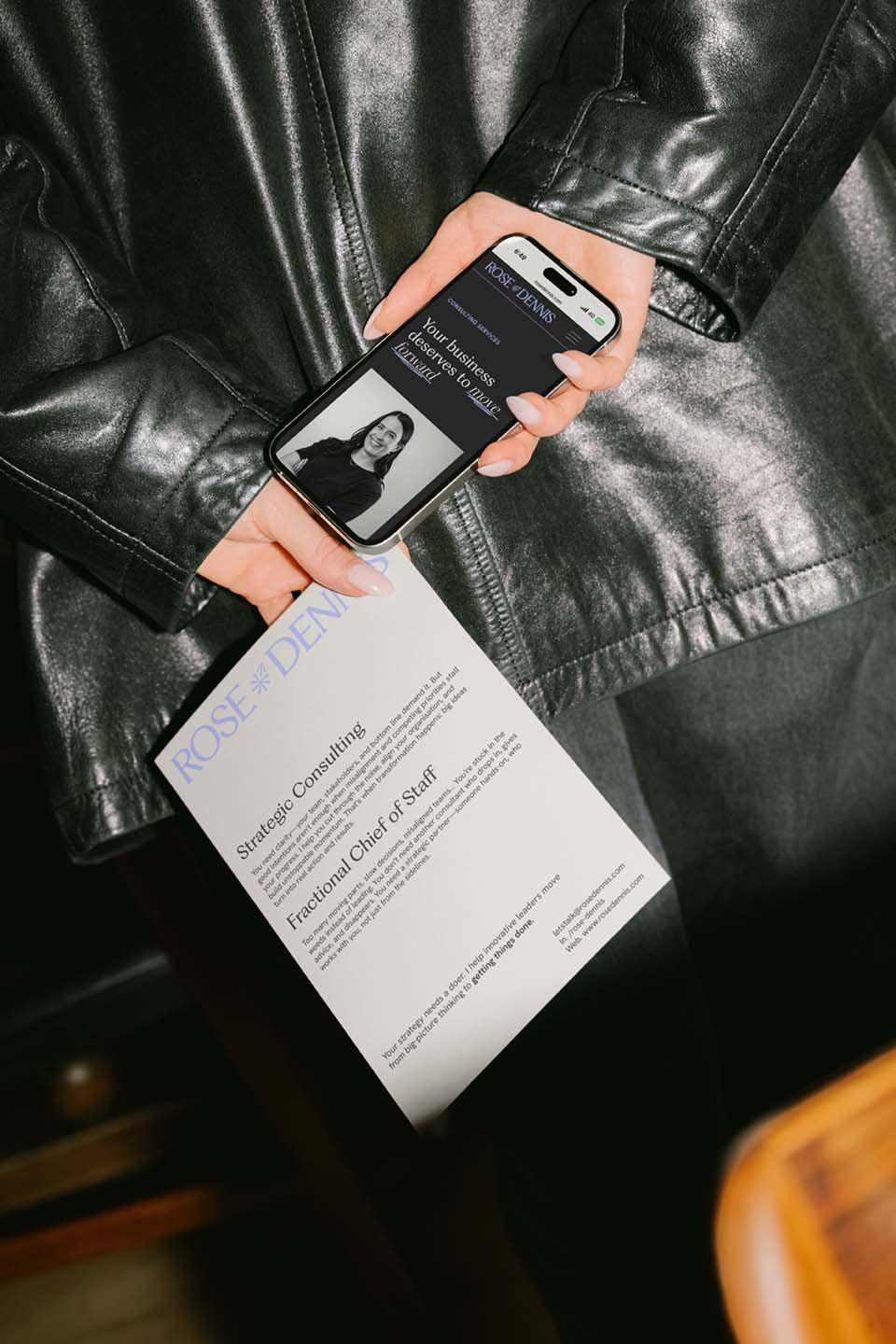 Woman wearing black leather jacket holding flyer and phone for Rose Dennis consultancy business