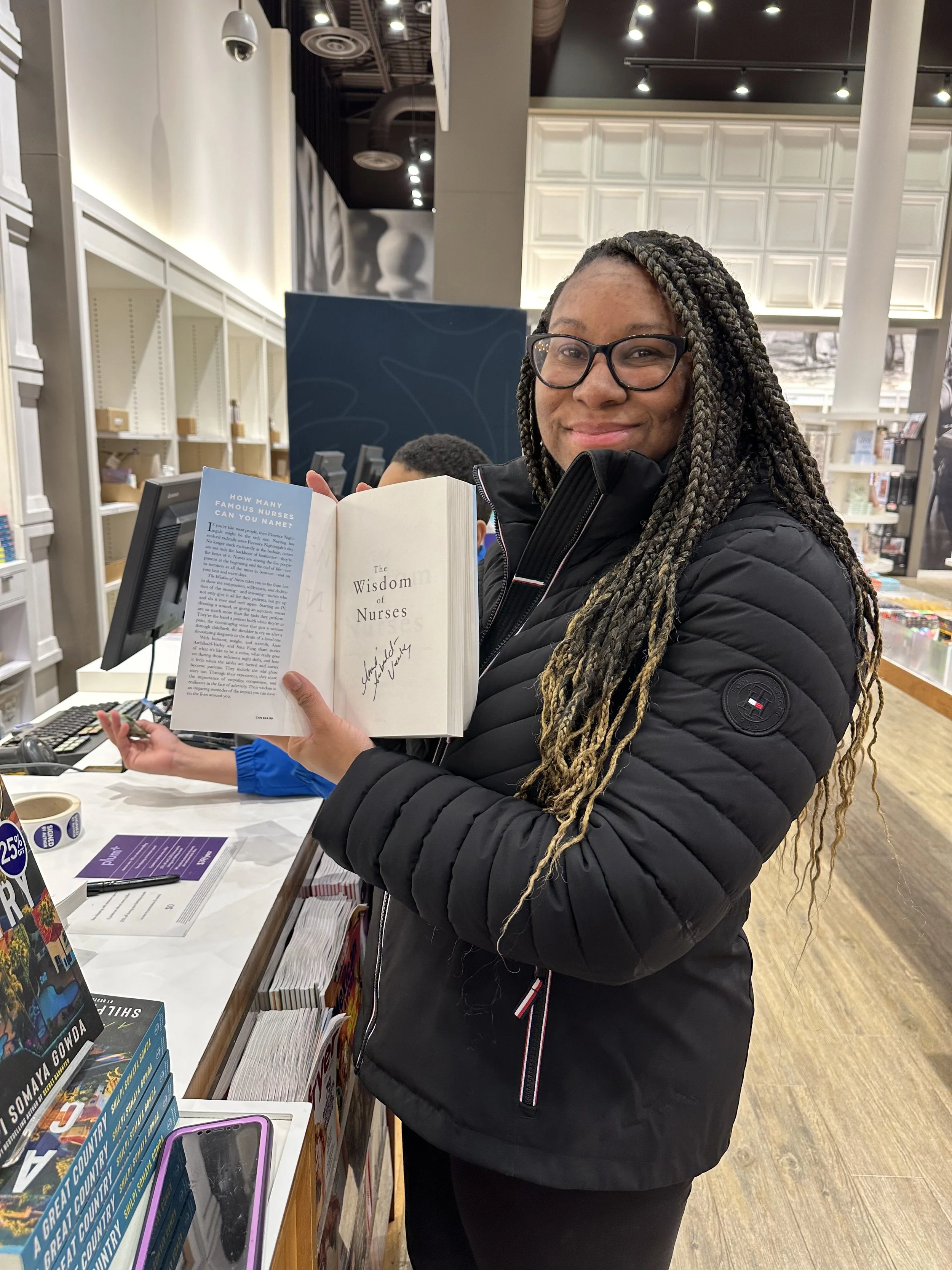 Amie holding her #1 National BEst Selling book in Chapters with it signed and open to the first page of The Wisdom of Nurses