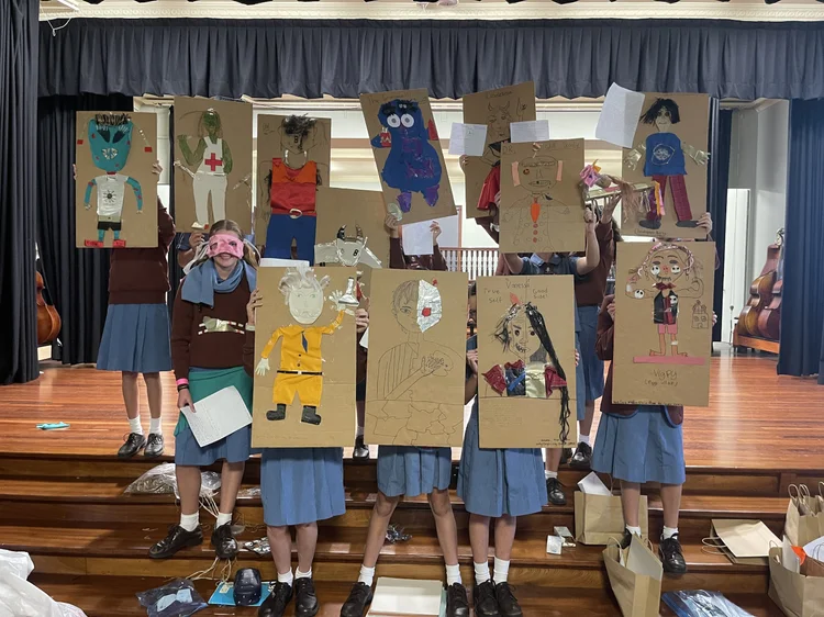 Students holding imaginative mixed-media figures