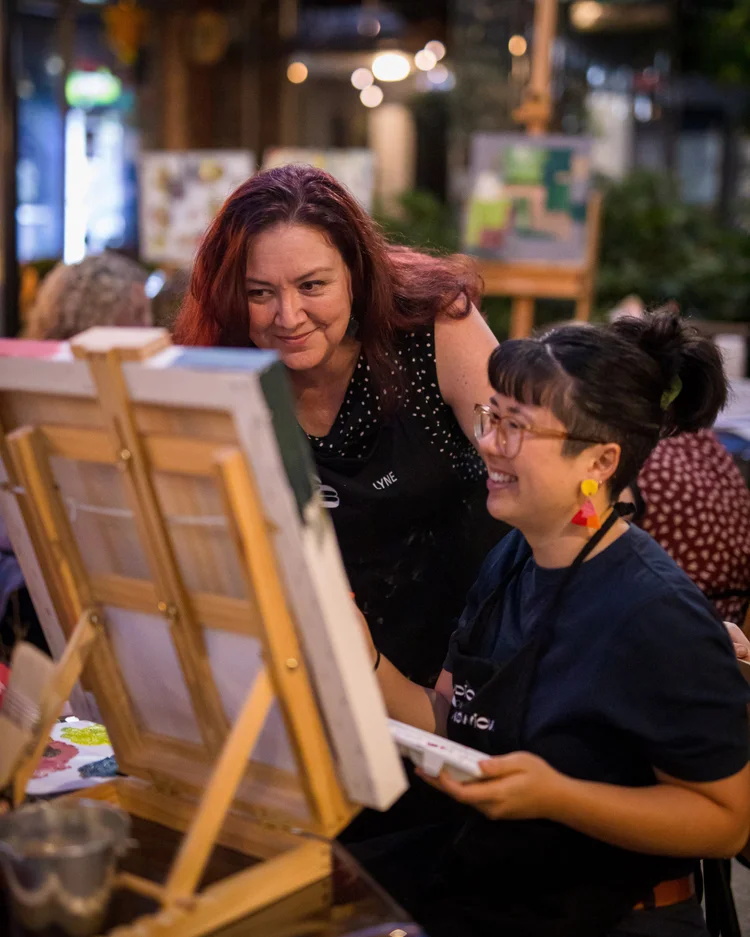 Lyne helping an artist during a painting workshop