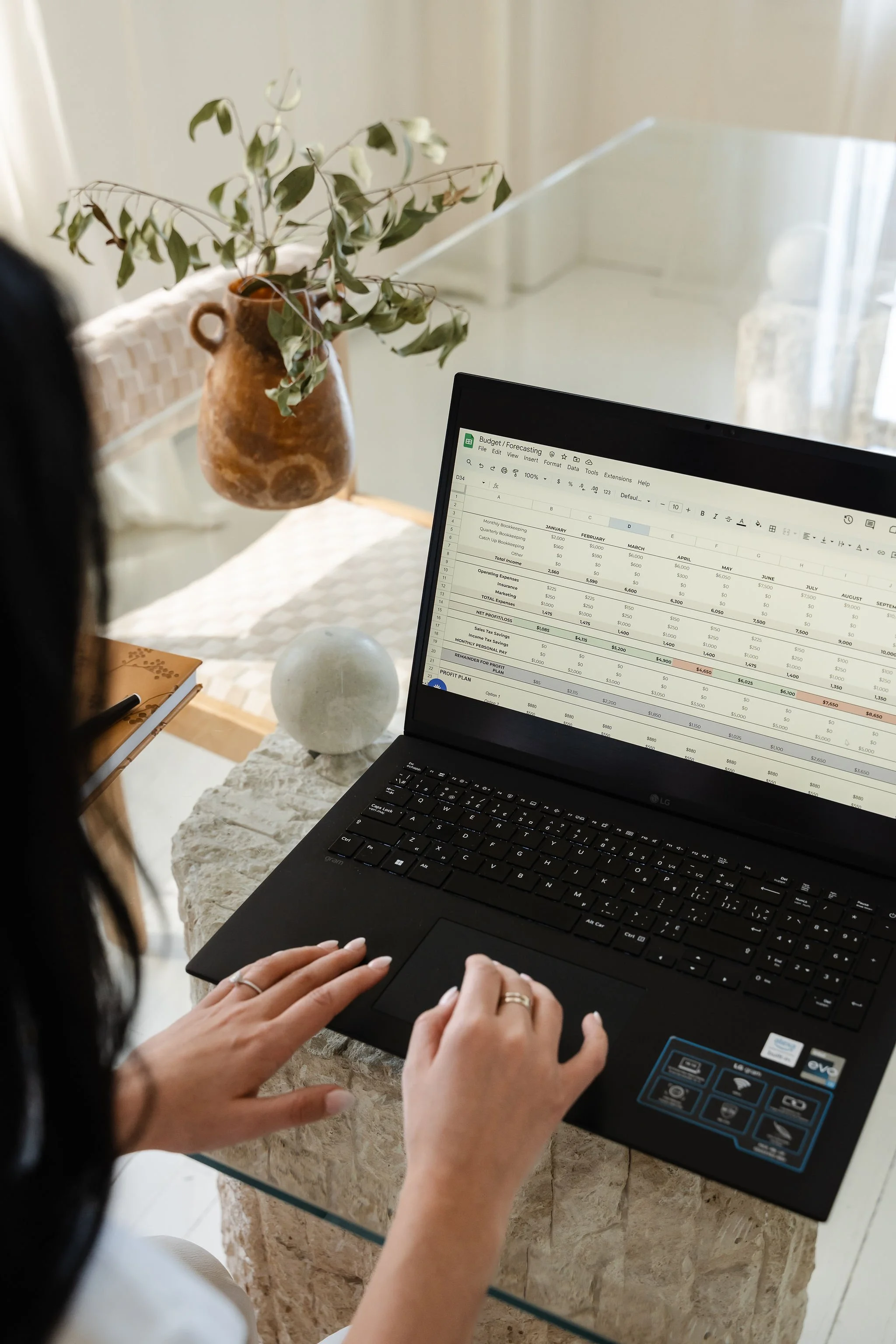 Close-up of hands typing on a laptop showing a bookkeeping spreadsheet
