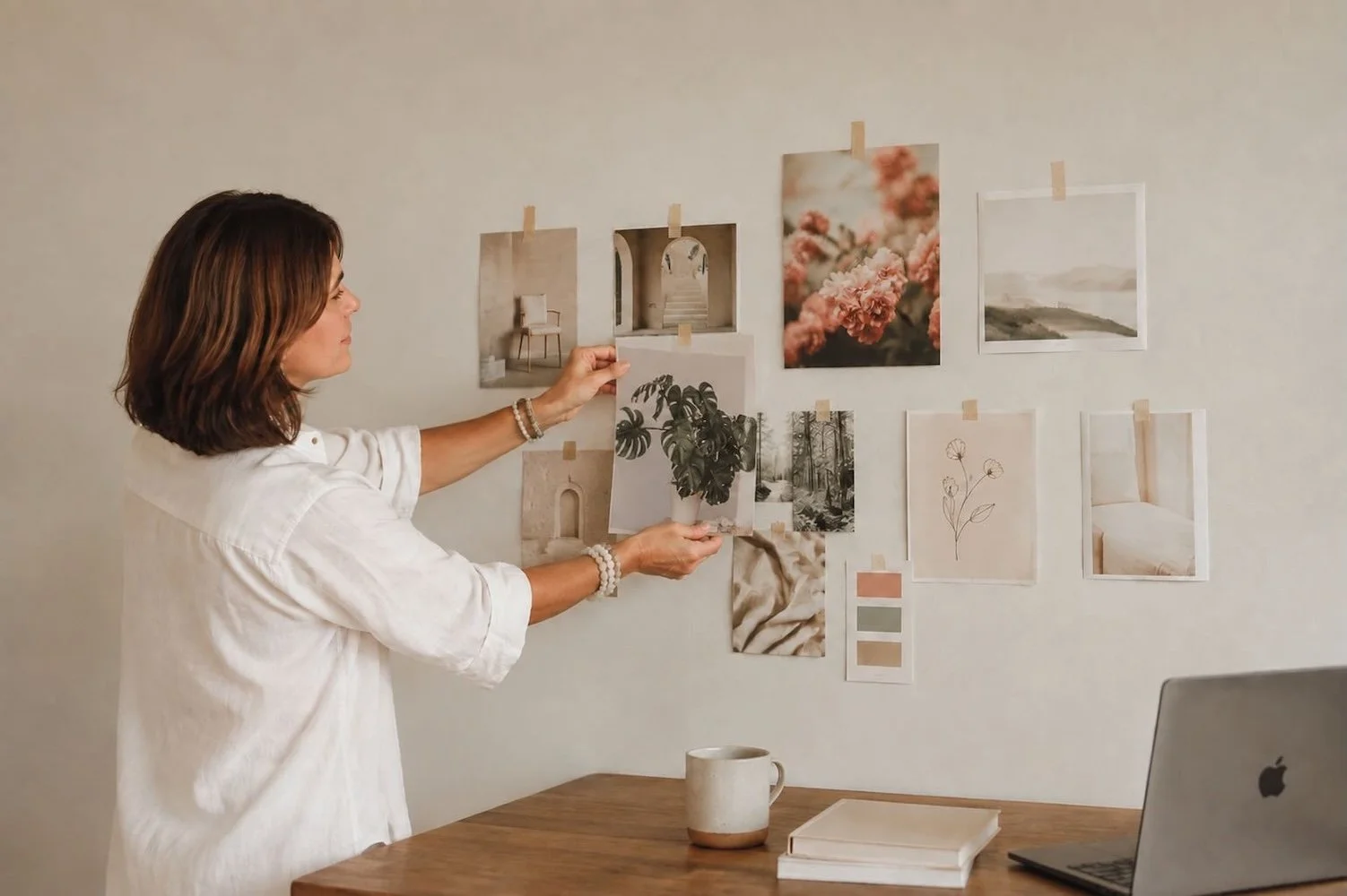 Marta arranging photos and images on a wall for a brand mood board.