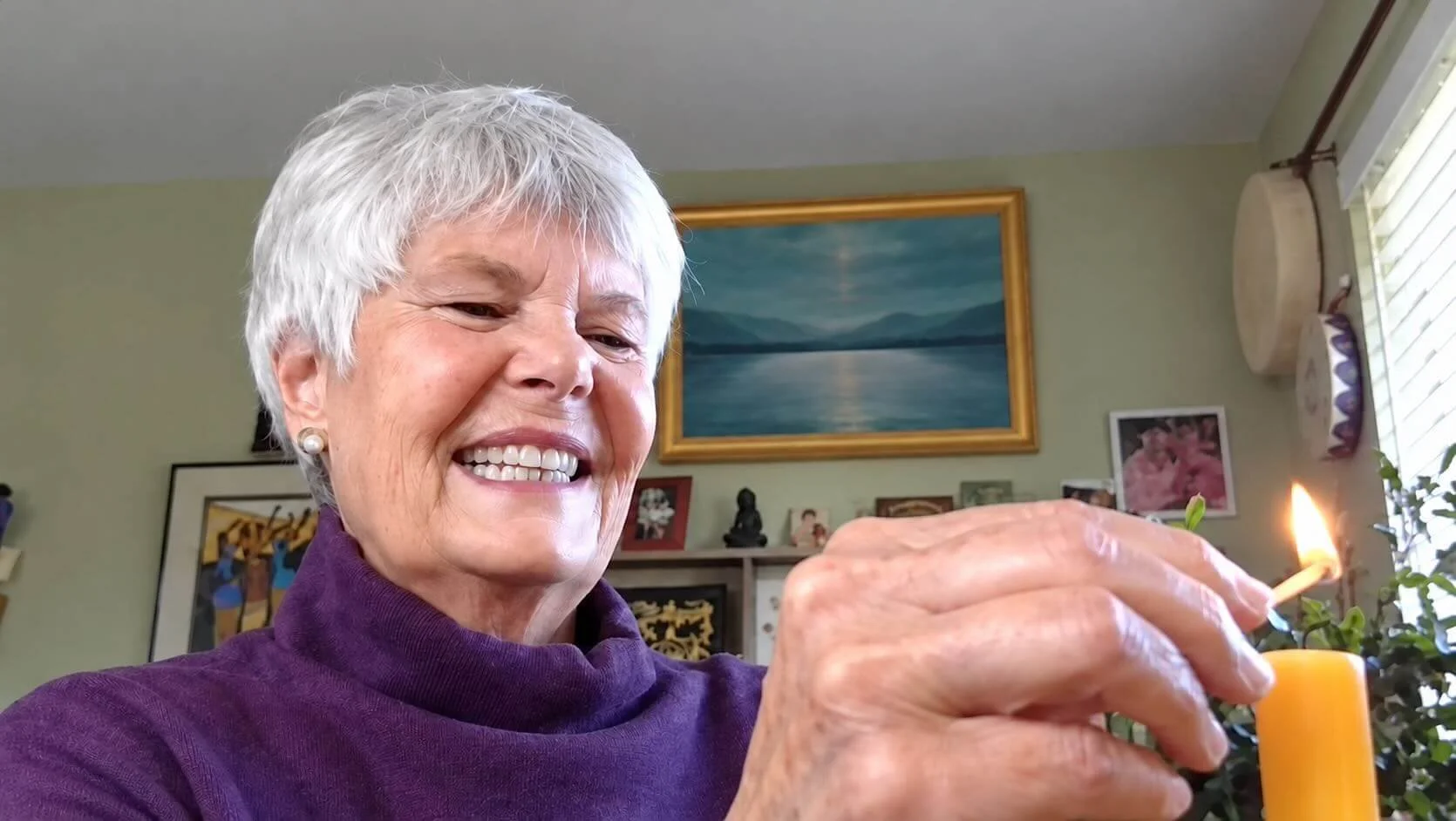 Terra Morgan smiling as she lights a yellow candle.