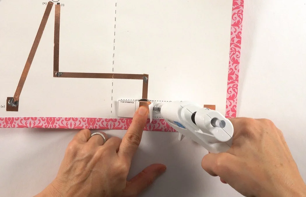 Hold the battery tightly in the pocket. Add hot glue under 1 paper tab.