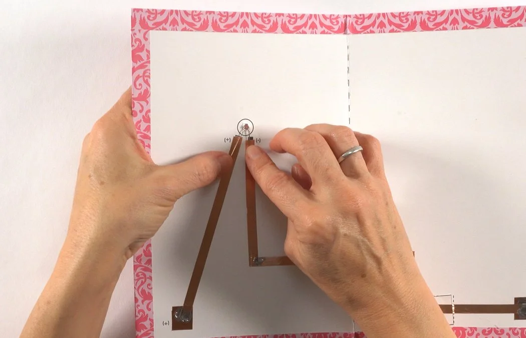 Bend both leads down to the copper. The (+) lead must touch the (+) copper. The (-) lead must touch the (-) copper.
