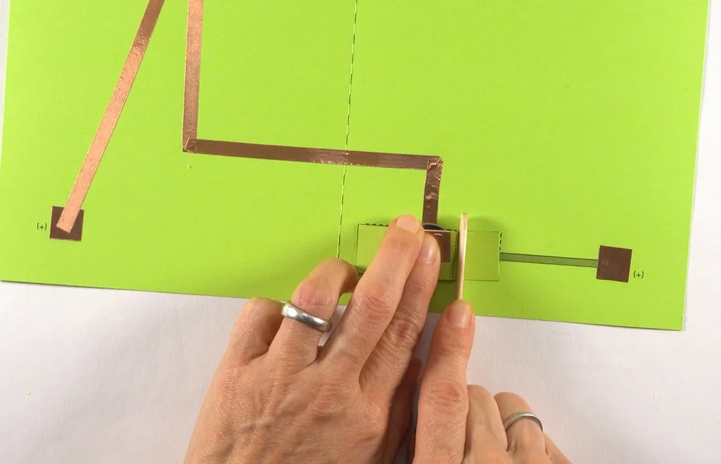 Place the tab in the hot glue. You can use a popsicle stick to press it down.