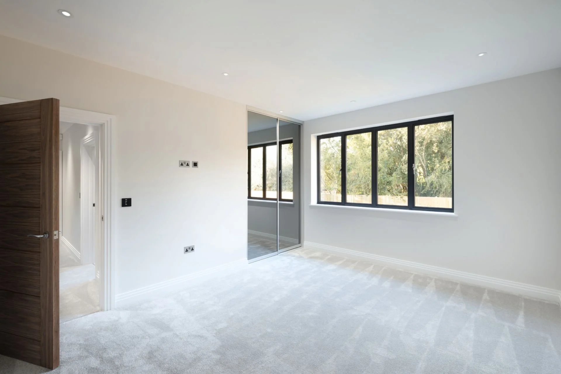 A mirrored sliding door, fitted wardrobes in a new build home in Surrey.