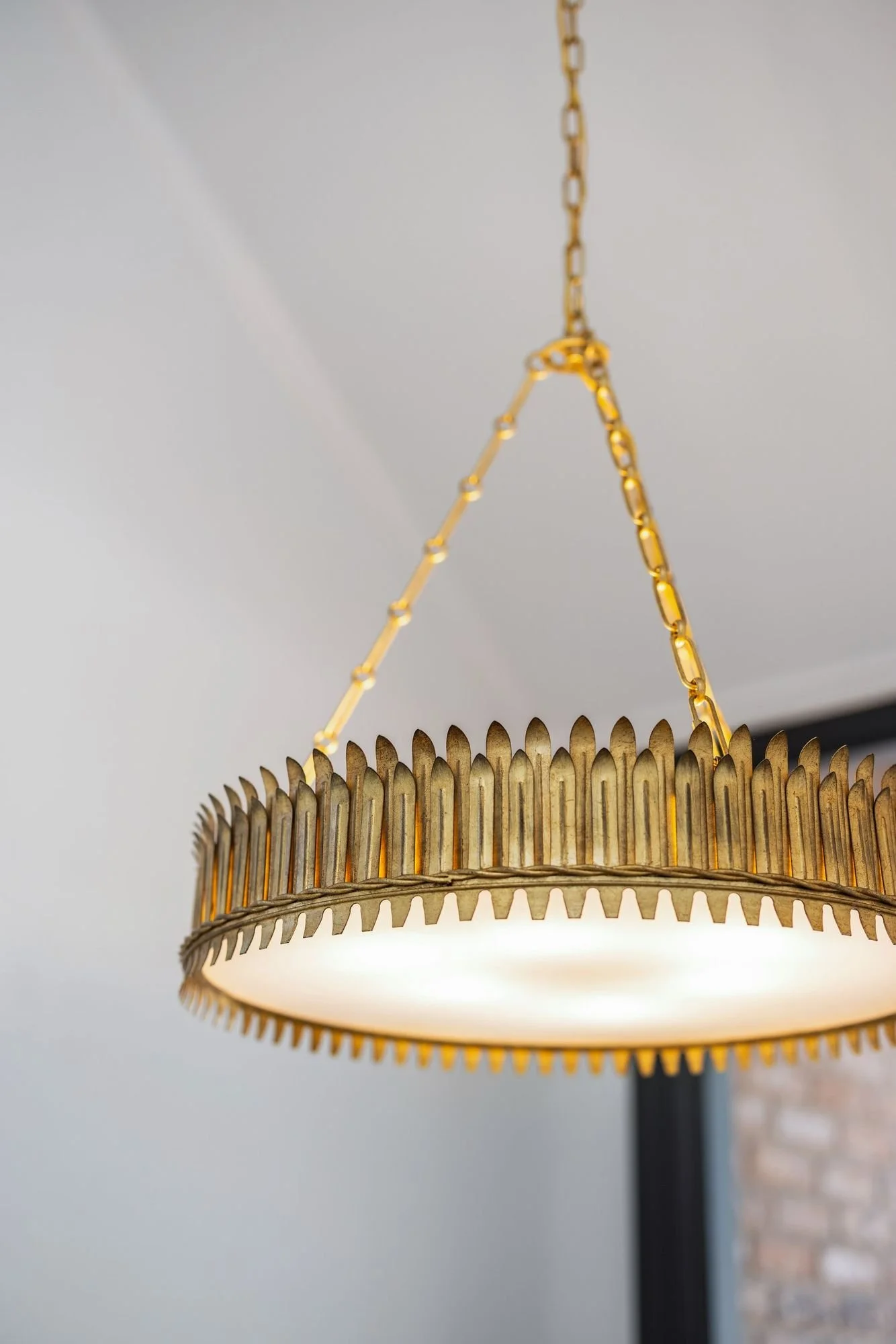 Brass ribbed pendant light against a white ceiling