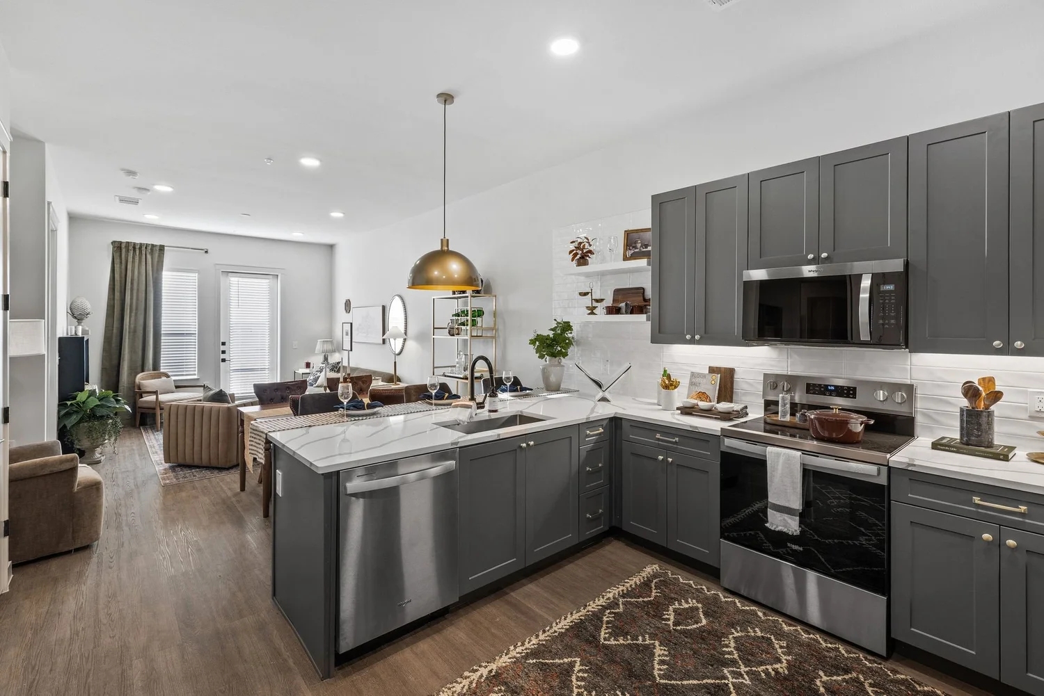 Model unit kitchen with charcoal cabinets and gold pendant light