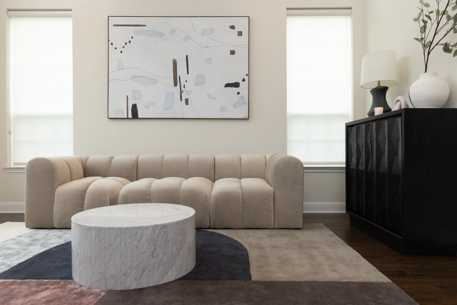 Cream channel sofa, marble table and abstract art in a staged living room