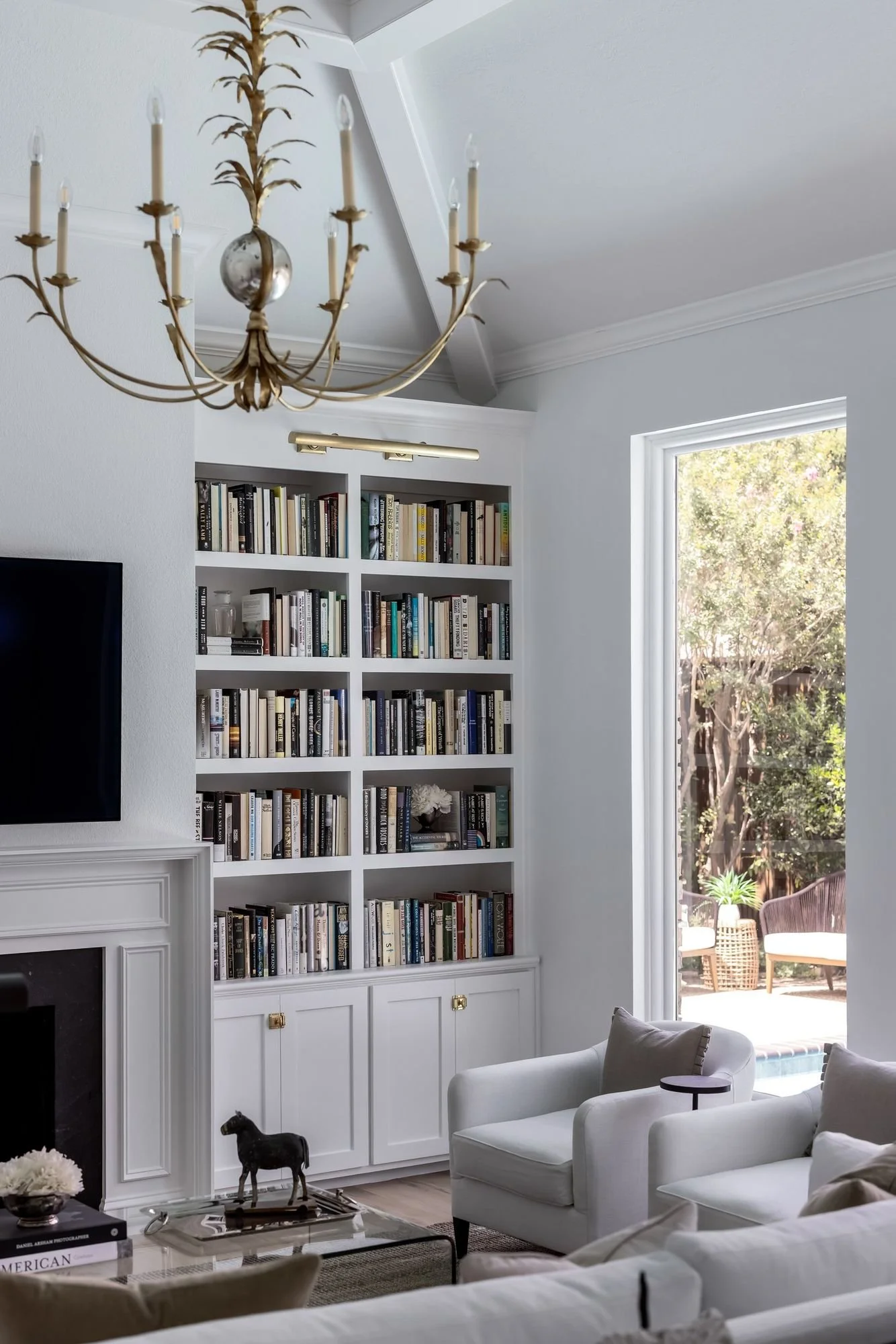 Brass chandelier above white built-in bookshelves