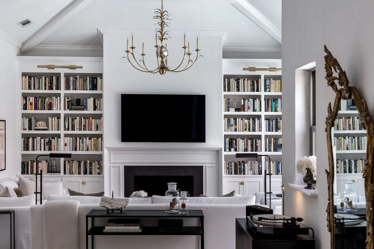 White built-in library wall with brass chandelier