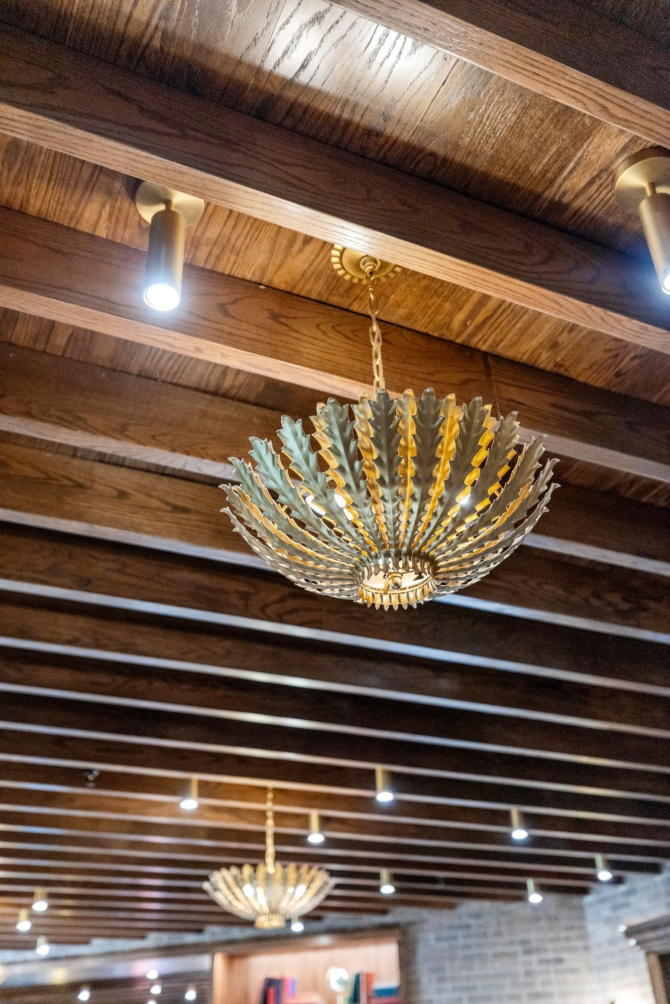 Gold sculptural chandelier against a wood-slat ceiling