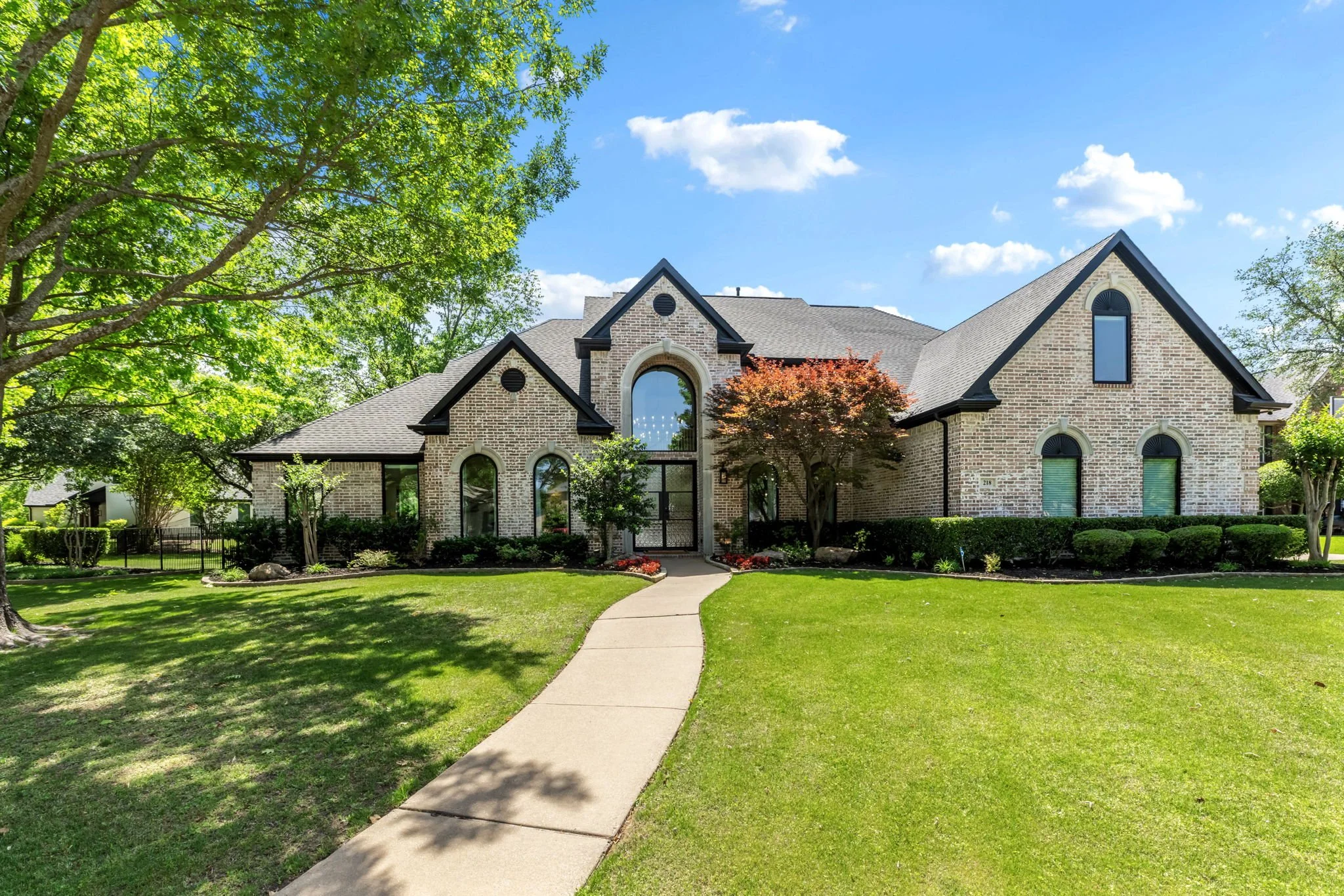 Stone home with arched windows and a long front lawn
