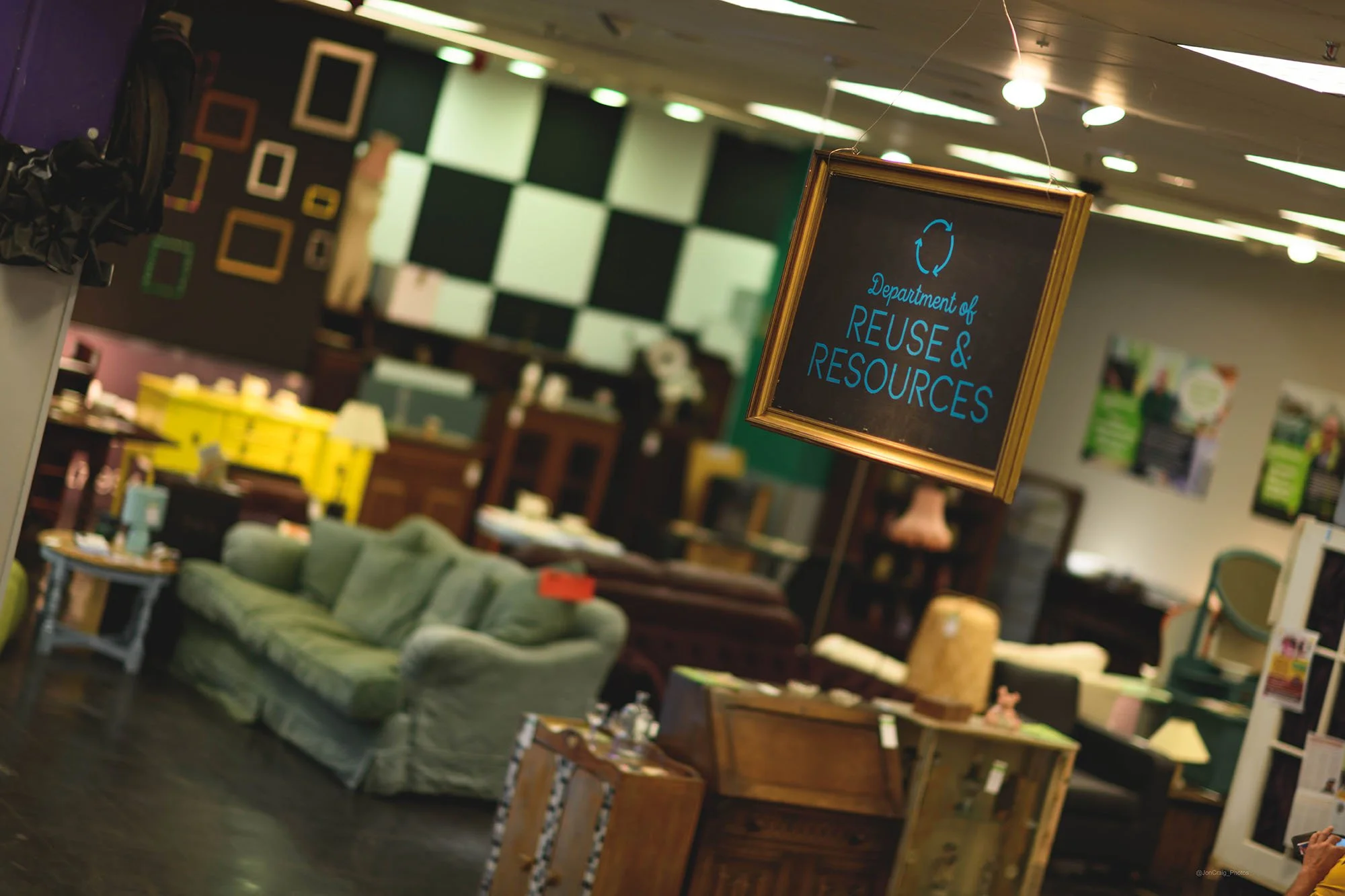 Furniture items displayed in a store, including sofas and chairs, with a sign hanging that reads "Department of Reuse & Resources" inside of Sparks Bristol.