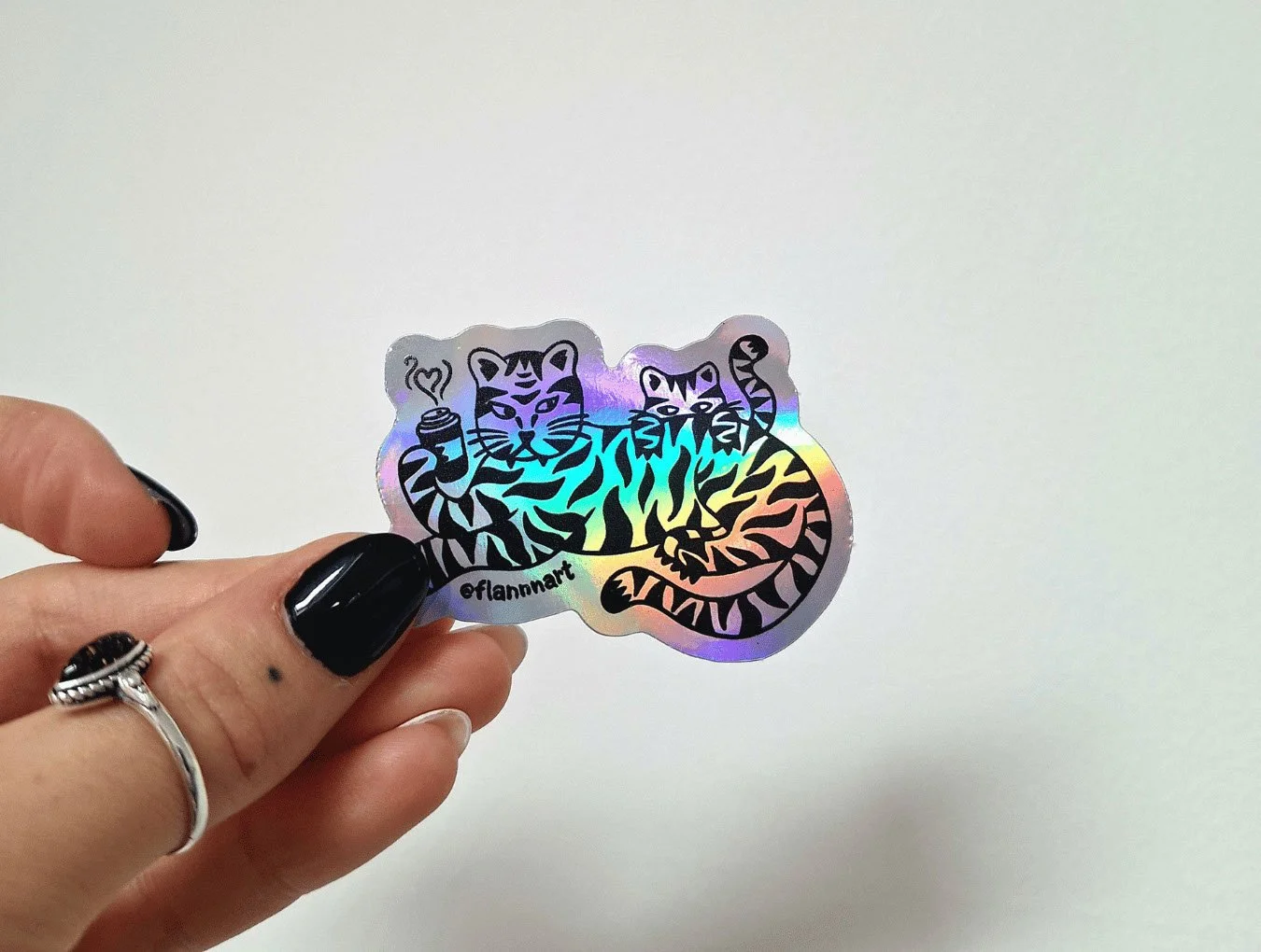 Holographic sticker featuring two cartoon tigers, one holding a cup of coffee. The sticker was designed by Sprout Design.
