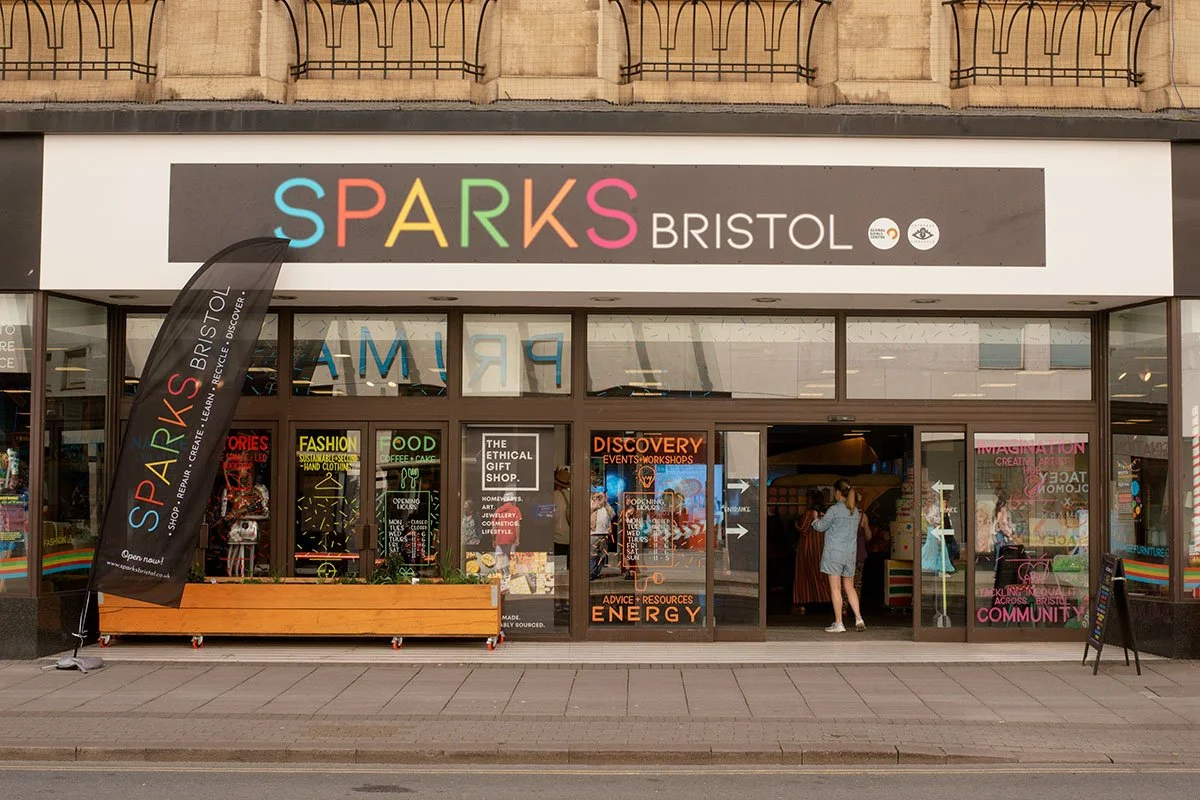 The storefront of Sparks Bristol, with colorful signage and banners, glass doors, and people entering.