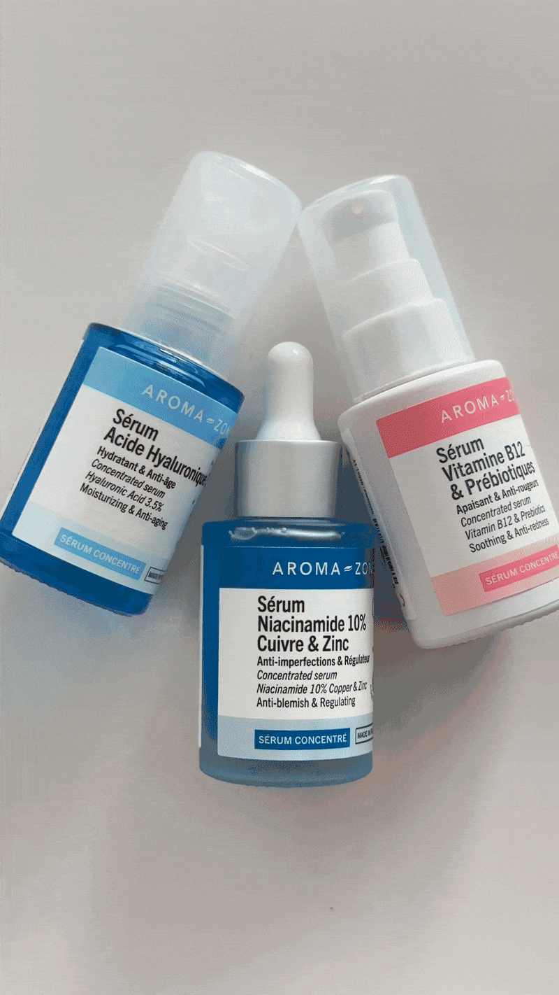 Three bottles of skincare serums with different labels and a dropper on a light-colored surface.