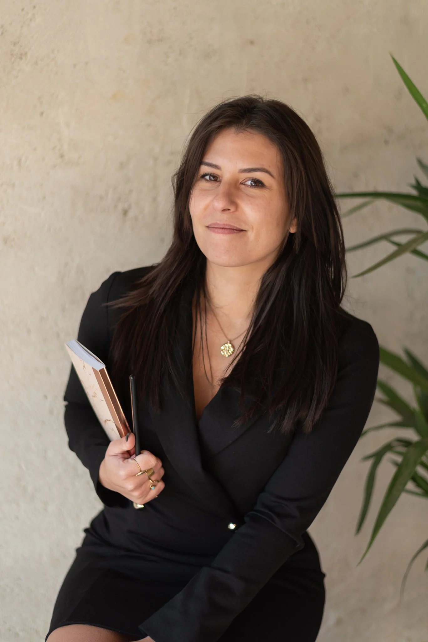 headshot of a business woman, social media manager looking at the camera with a notebook under her arm