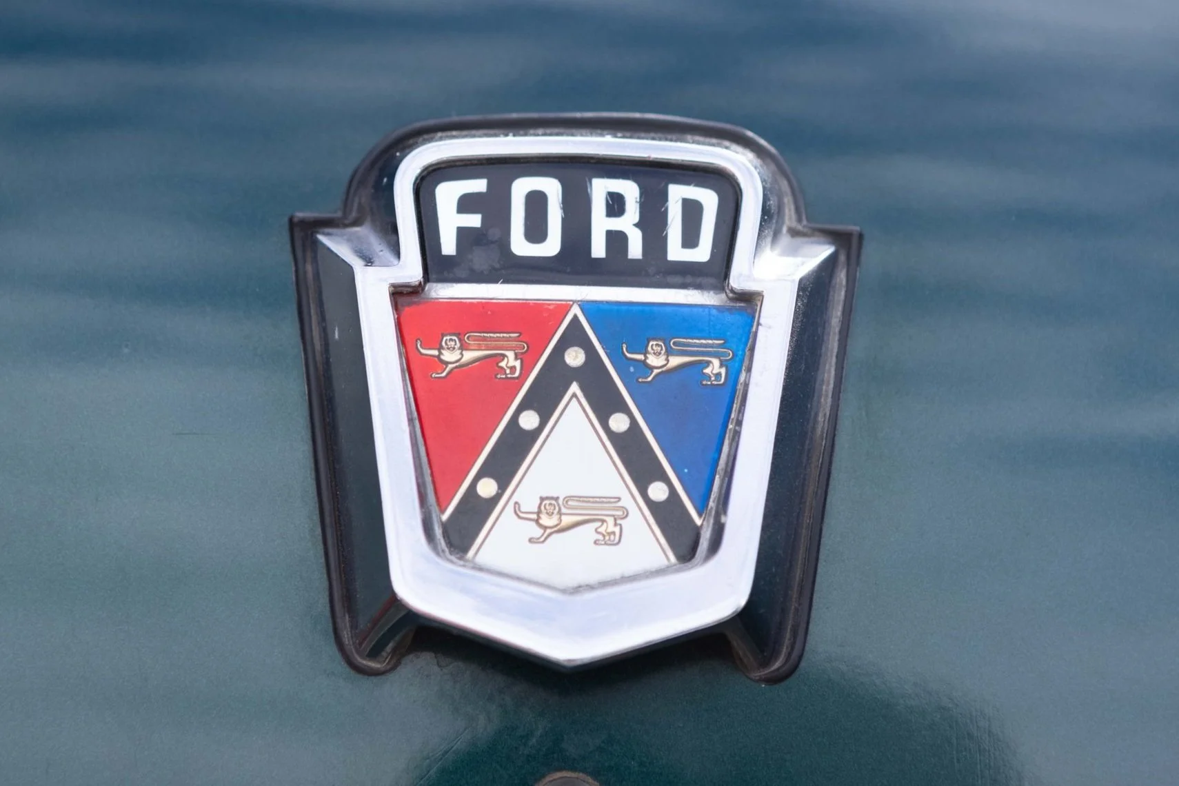 Ford emblem on a vintage car with a red, white, and blue crest featuring lion symbols.