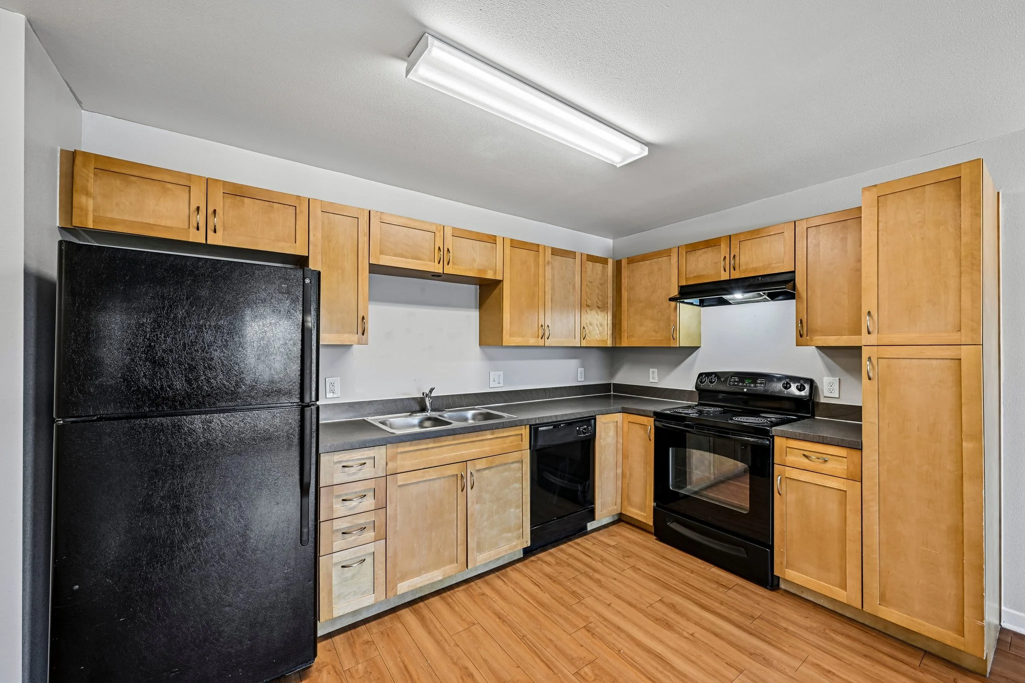 Kitchen with wooden cabinets, black appliances, and a wooden floor