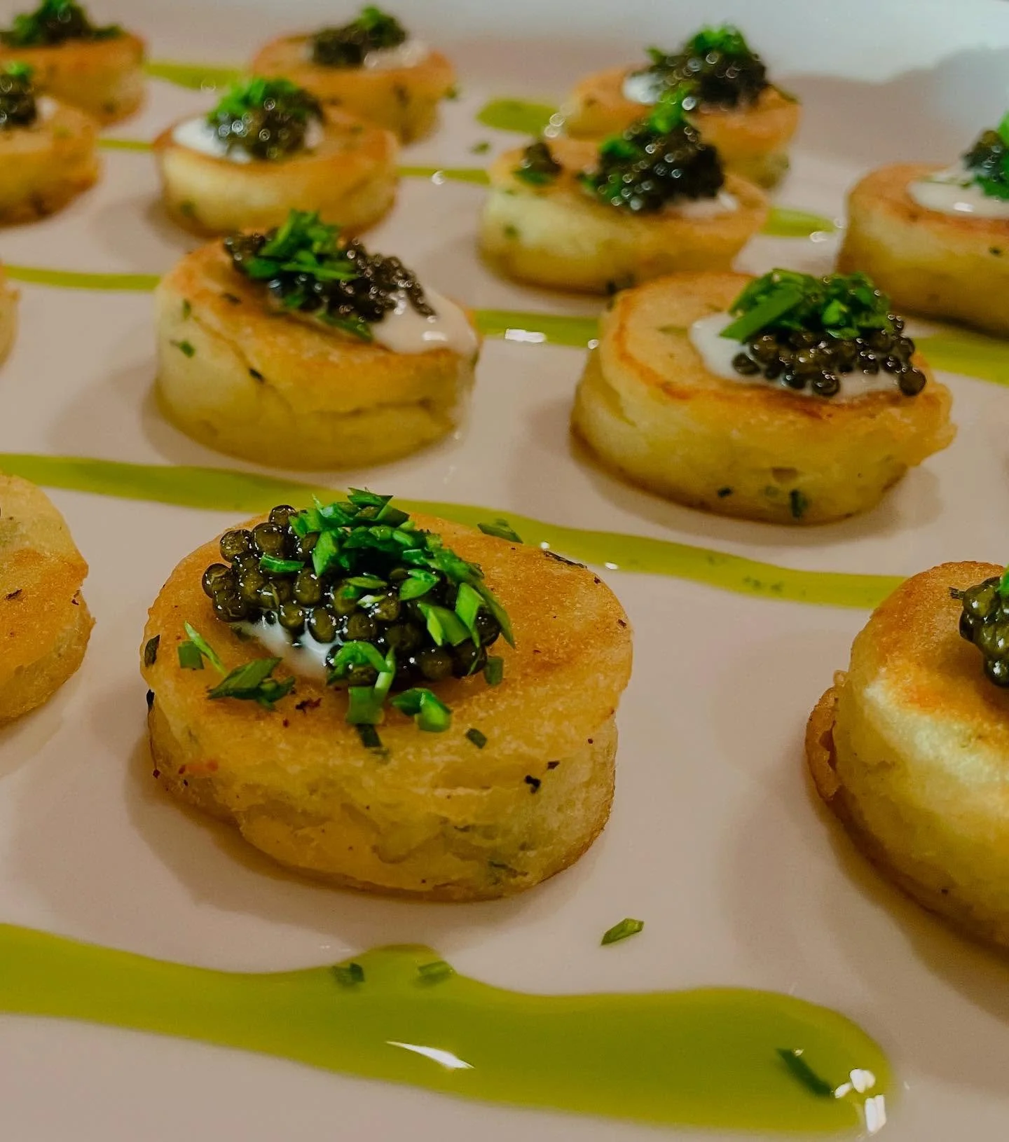Golden, crisp potato cakes topped with a dollop of tangy crème fraîche and finished with a generous spoonful of Petrossian Royal Ossetra caviar—this elegant bite delivers a luxurious balance of textures and briny umami. A touch of