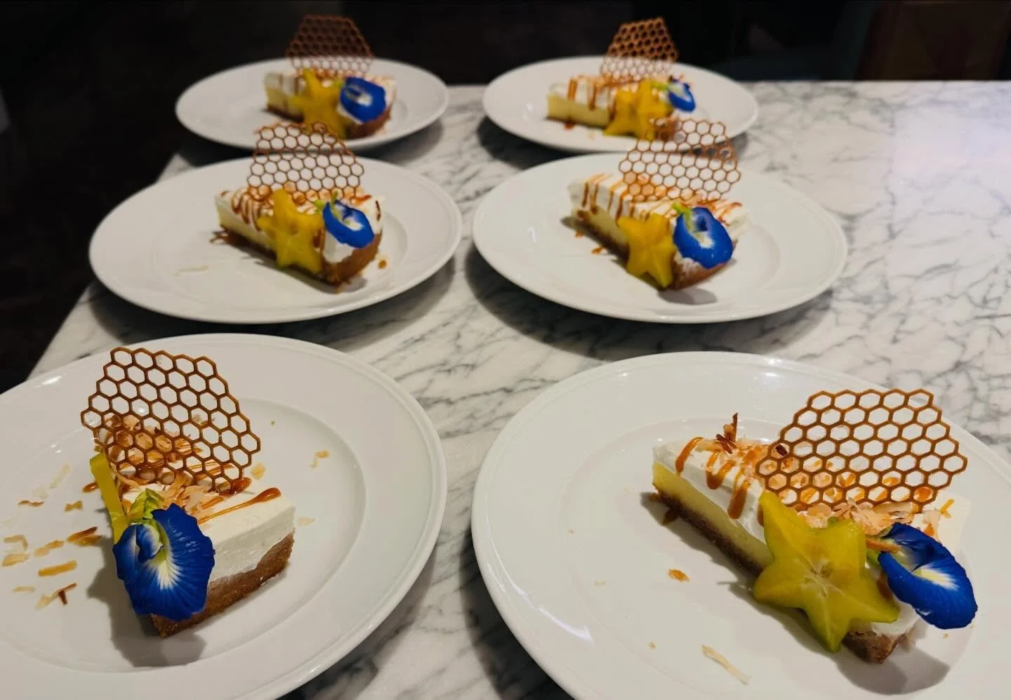 Silky coconut cream pie with a buttery crust, layered with rich coconut custard and finished with a light cloud of whipped cream. Garnished with tropical fruit, toasted coconut, and a delicate caramel crisp&mdash;classic, elegant, and unmistakably is