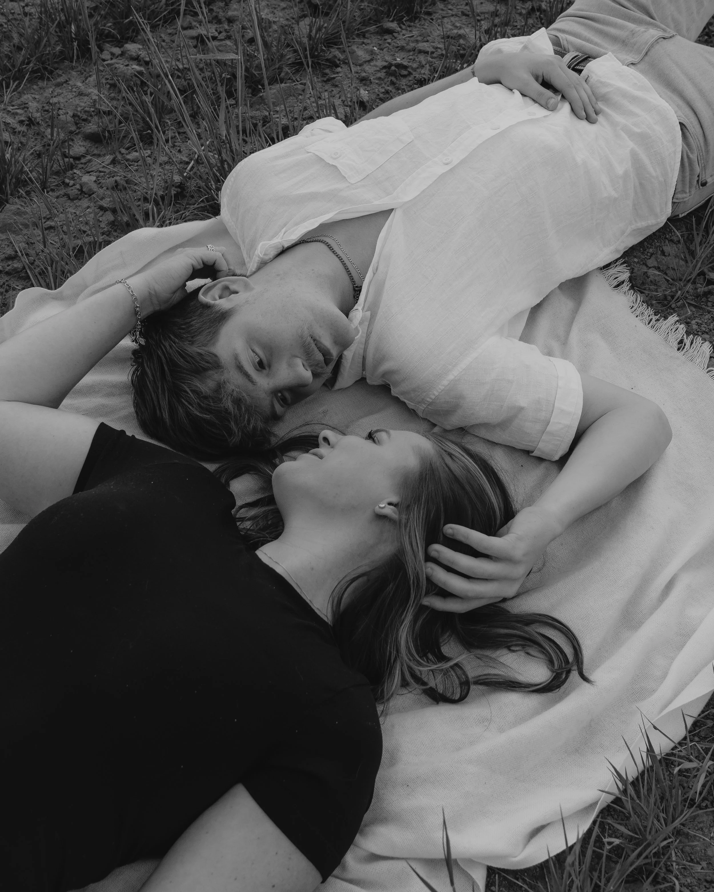 Couple lying together on blanket, intimate black and white lifestyle portrait with romantic mood