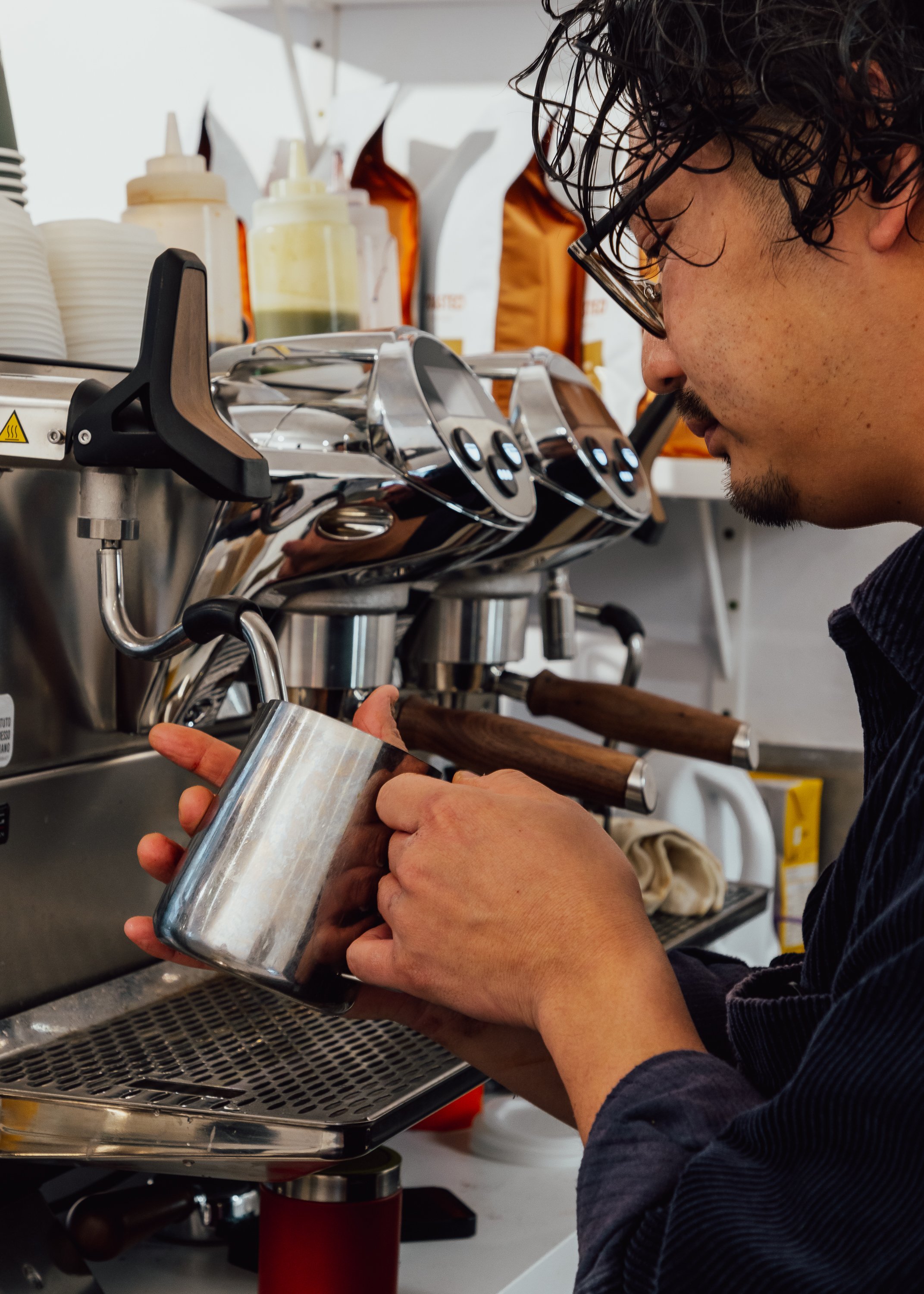 Close-up of a barista steaming milk with espresso machine in Auckland cafe