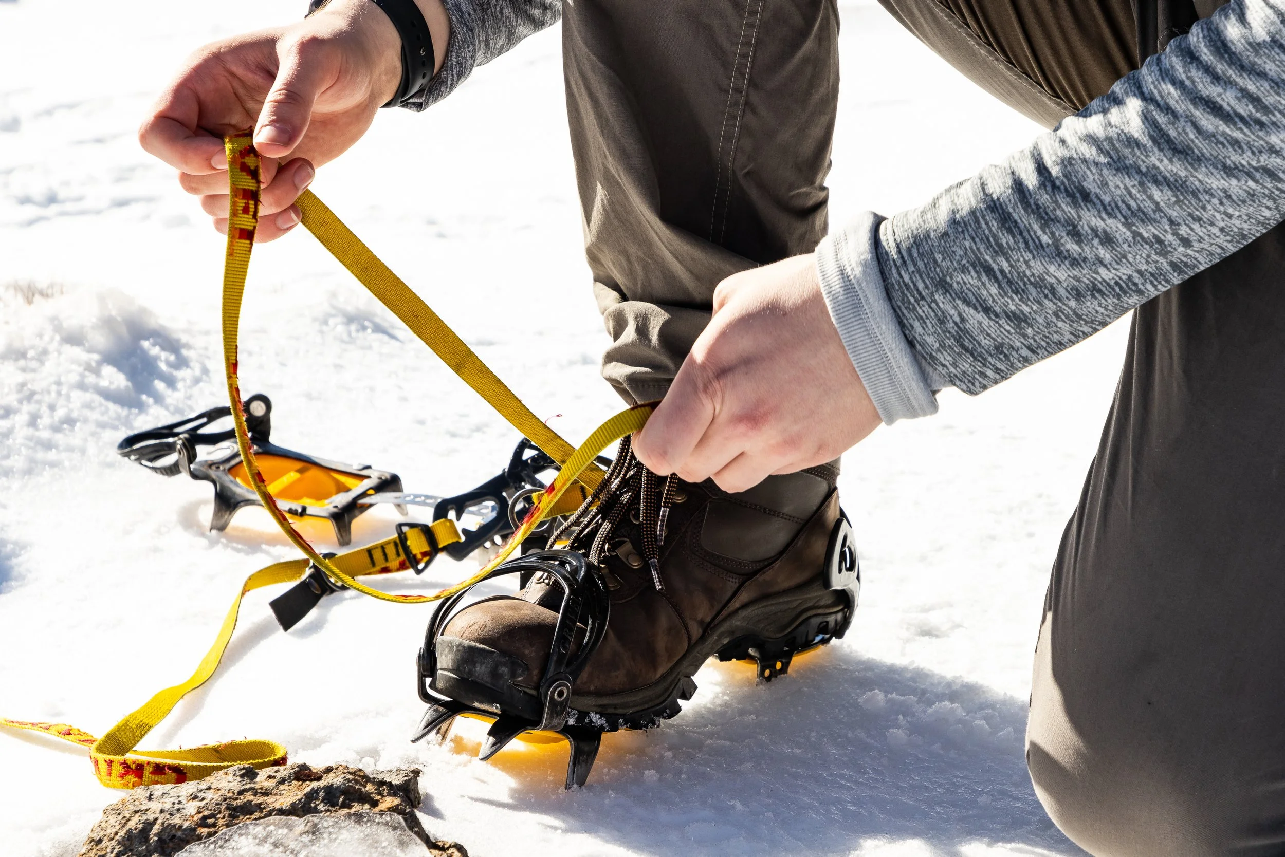 Hiker putting on crampons for icy trail on the Tongariro Alpine Crossing in New Zealand