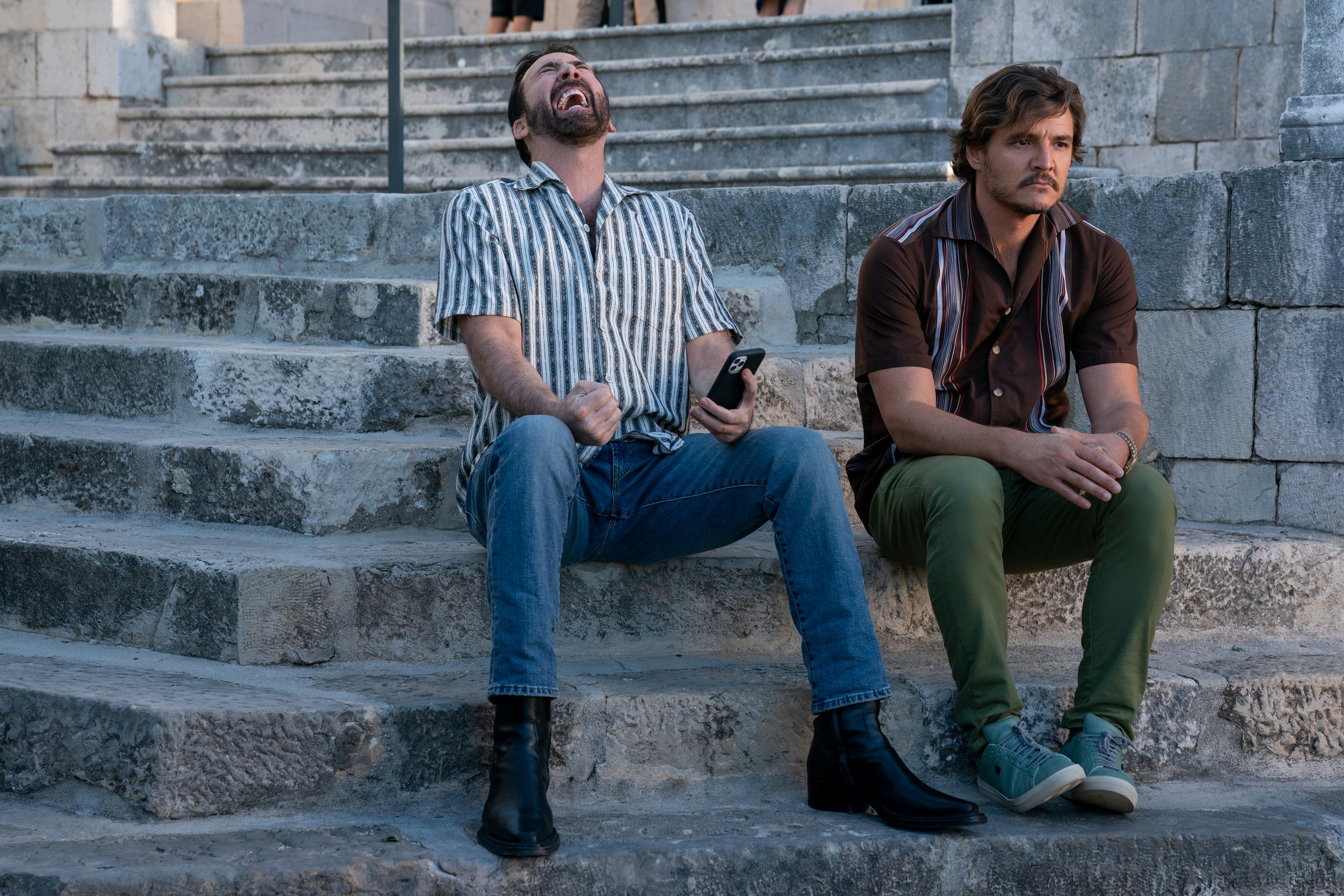 Javi Gutierrez' (Pedro Pascal, left) and 'Nicolas Cage' (Nicolas Cage, right) zooming through the mountains of Mallorca, Spain. Photo Credit: Katalin Vermes/Lionsgate