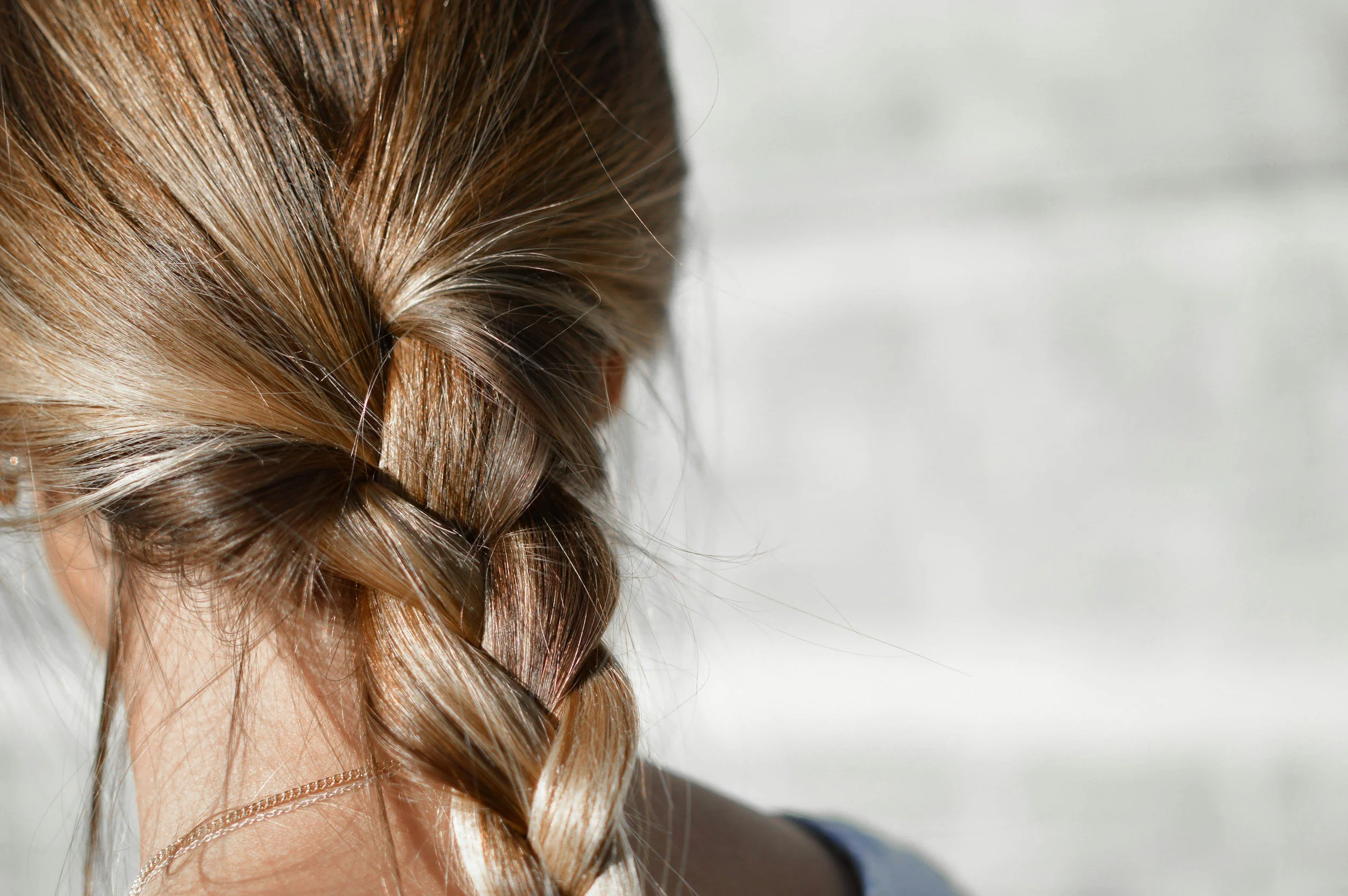 Close-up of a woman's blonde braided hair against a blurred background.