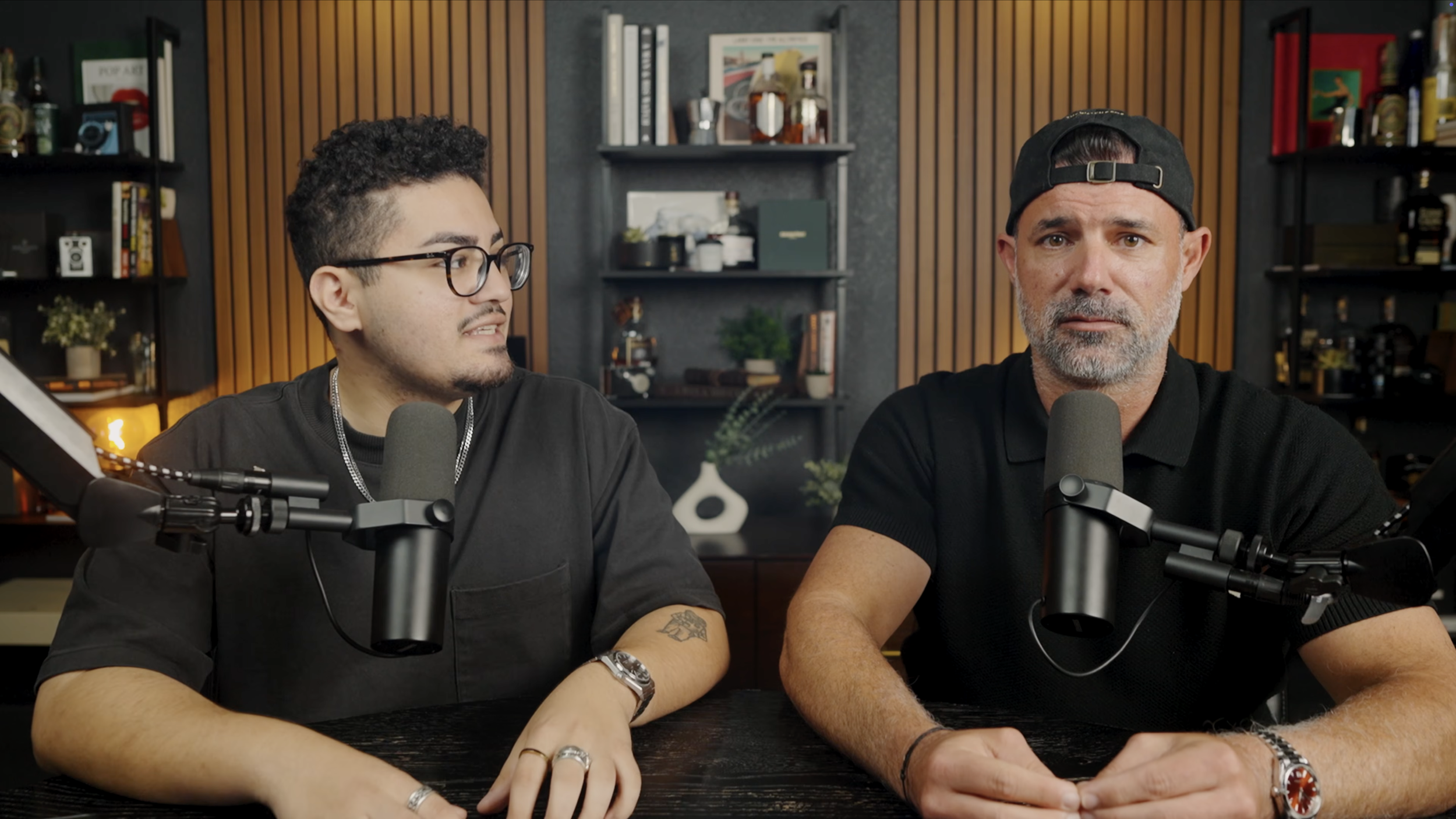 Two hosts recording a podcast with broadcast microphones in the Pensacola studio.
