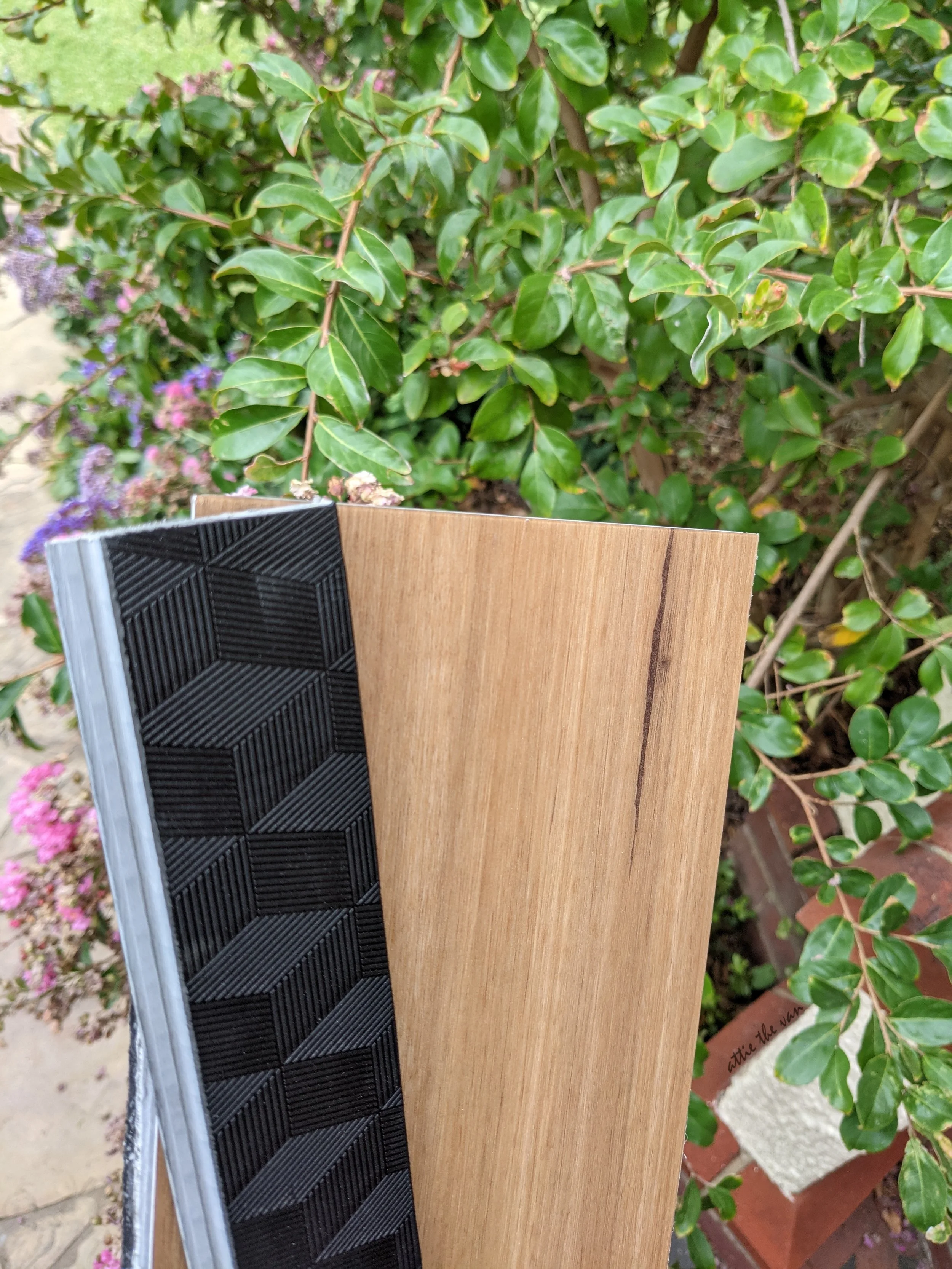 Front and back of hybrid flooring in front of bushes