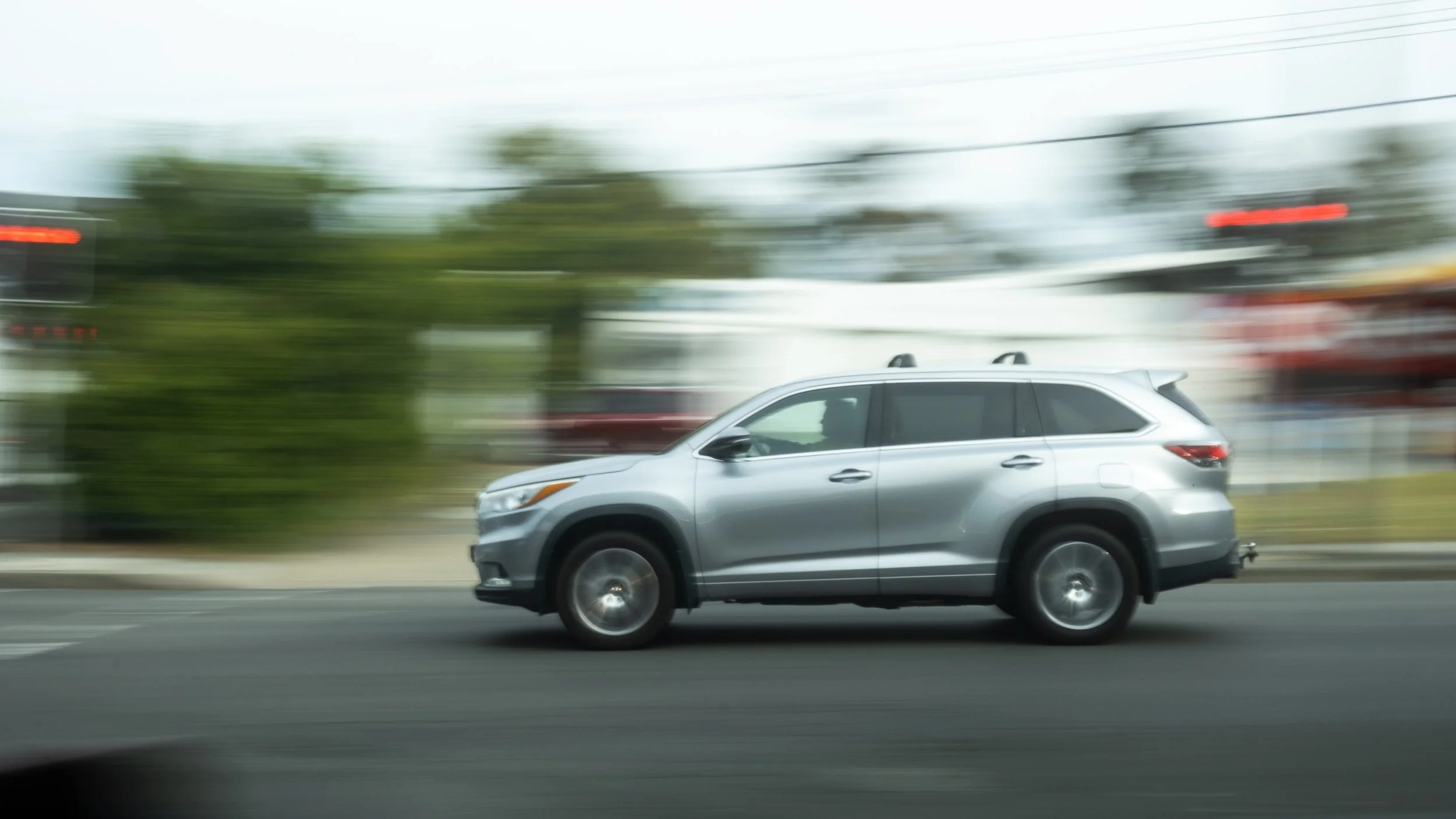 A silver SUV in motion on a city street with a blurred background due to motion