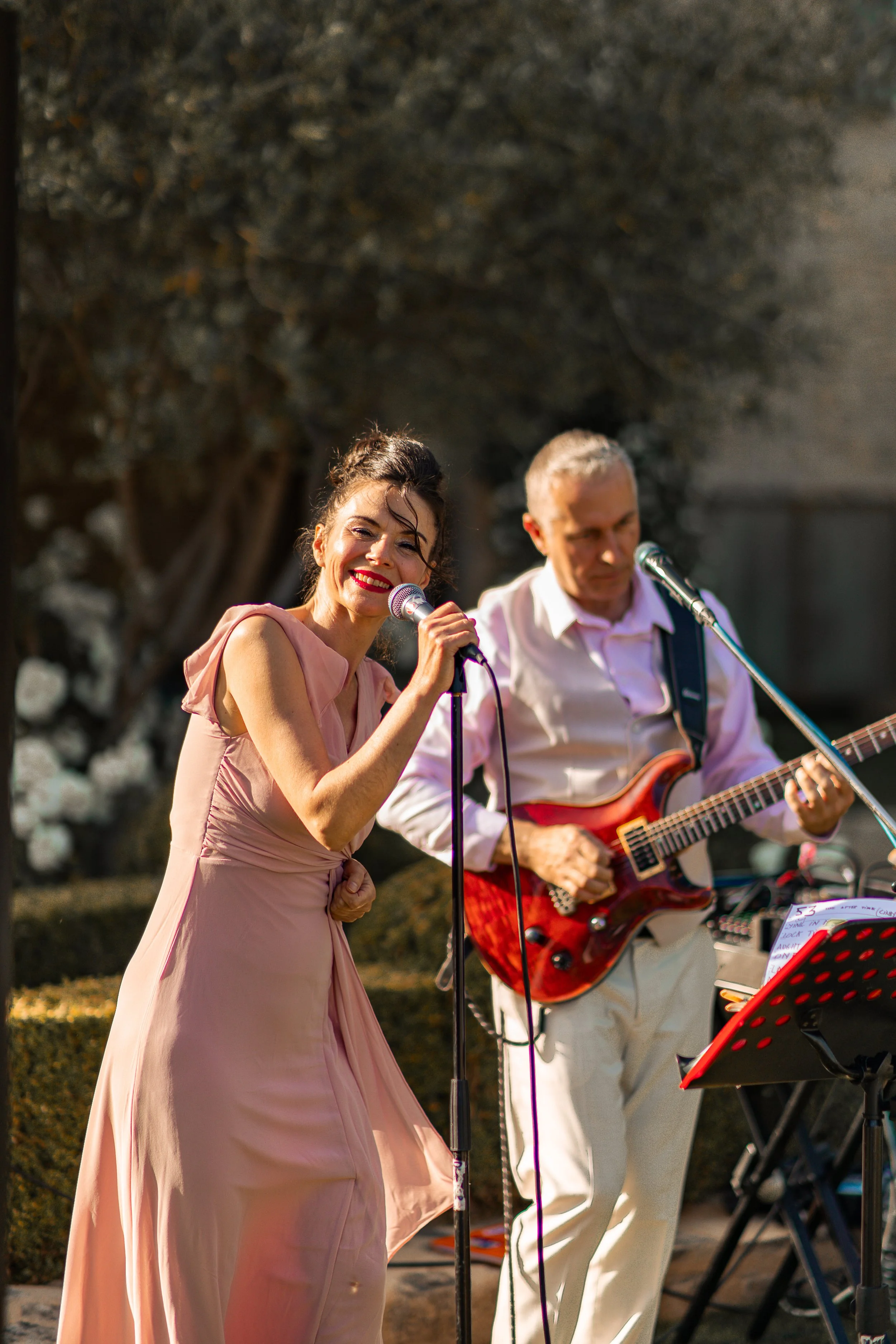 Une femme chante en faveur d'un groupe de musiciens jouant de la guitare électrique lors d'un vin d'honneur