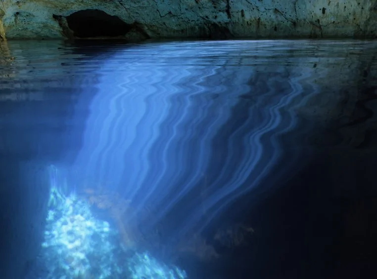 Rays of sunlight illuminate the crystal-clear water of this Yucatan cenote creating beautiful hues of blue and turquoise.