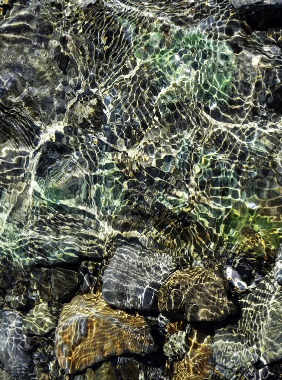 Ripples on the surface of Lake Pukaki, New Zealand, refract the sunlight on to the rocks below.