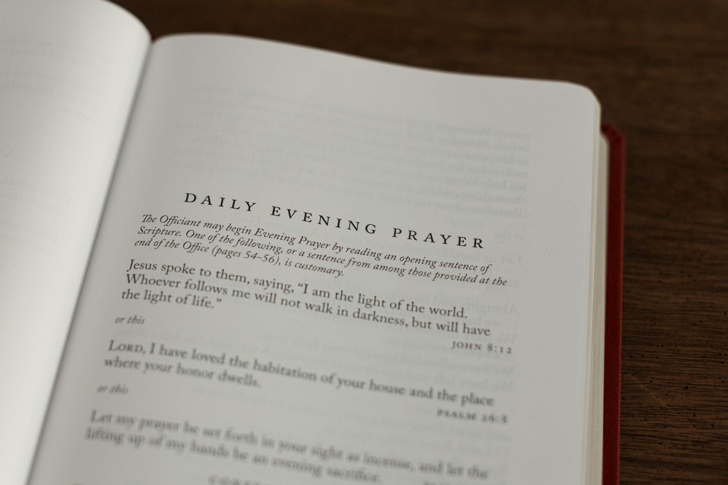 Open Bible with daily evening prayer page showing scripture and quotes on a wooden surface.