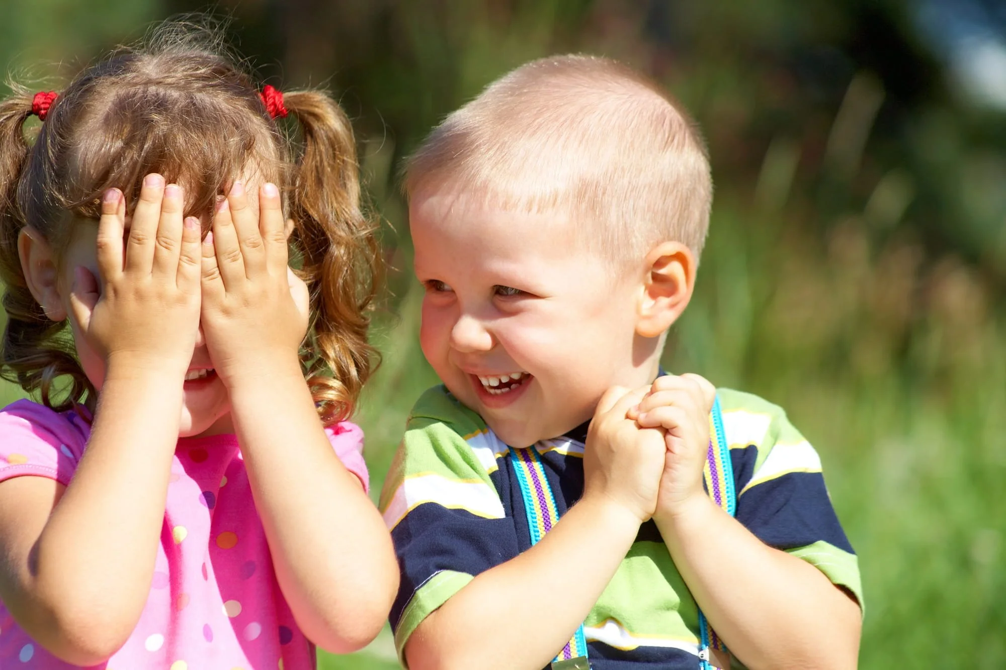 Toddlers playing peek-a-boo and laughing.