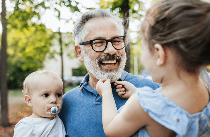 Middle-aged father holding his 2 children while laughing