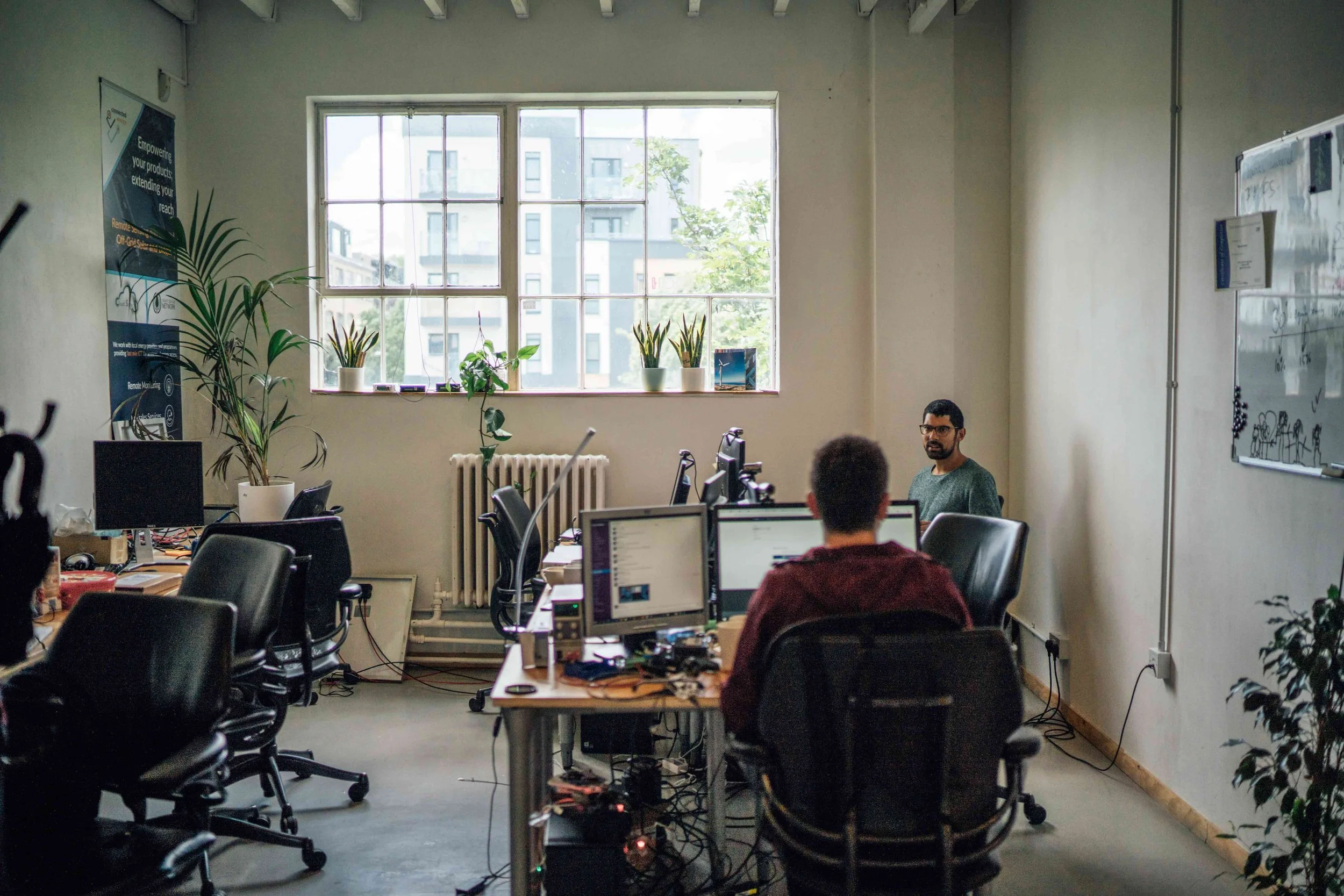2 people in an 8 person office in Hornsey North London  with large windows wooden desks