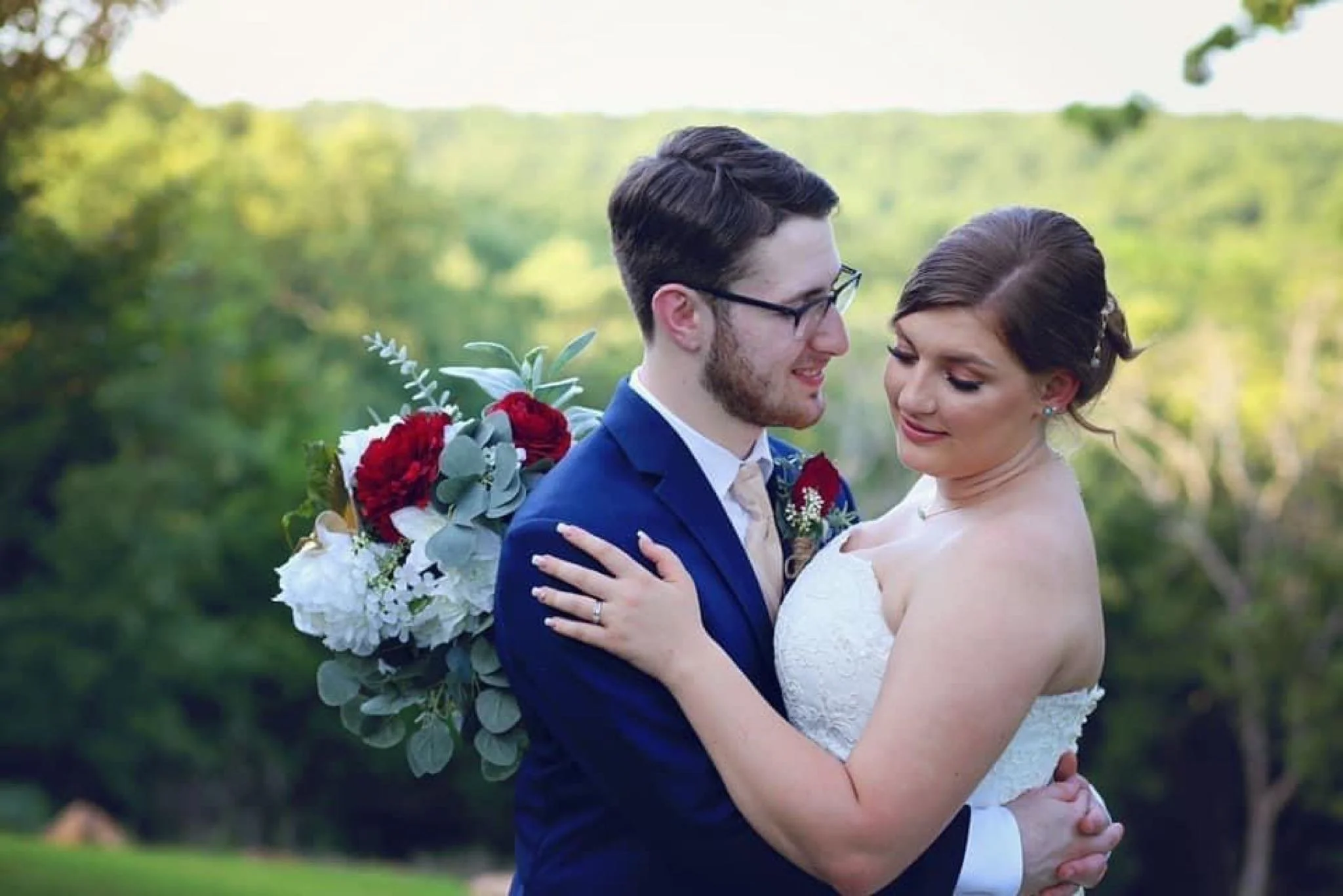 bride with strapless dress and groom with blue blazer holding each other 