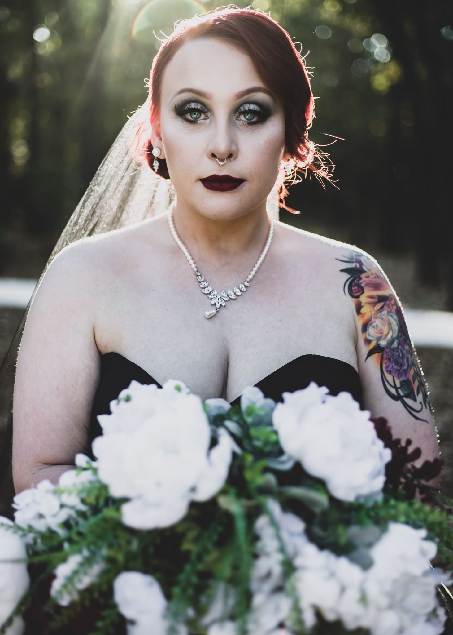 bride with black wedding dress and flower bouquet looking at the camera