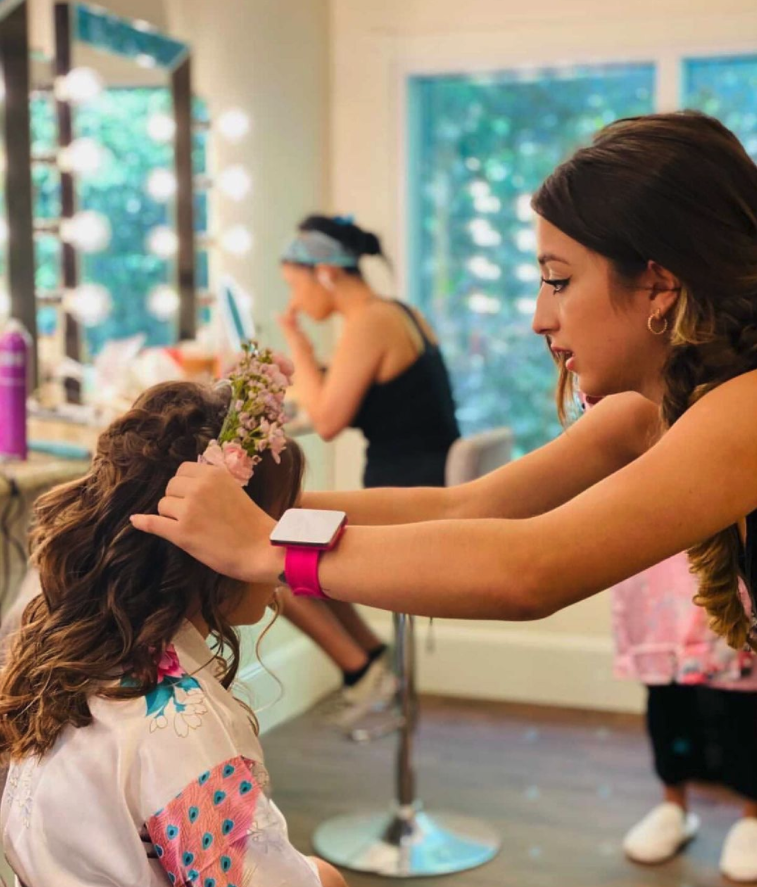 woman putting a flower headband on girl