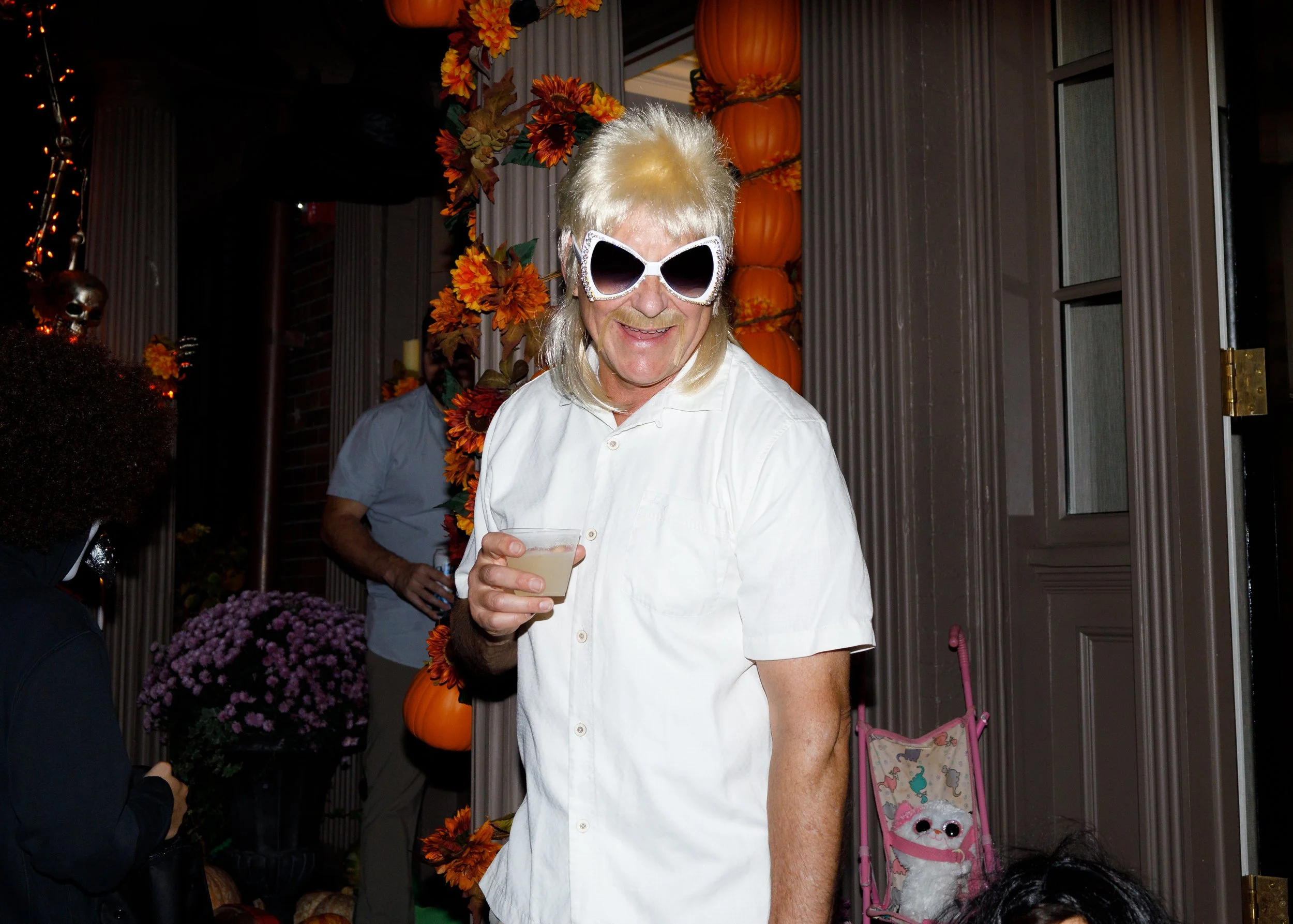 Boston, MA: October 31st, 2024: A Beacon Hill homeowner sips their drink while talking to kids about their costumes.