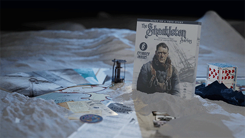 Scene of a tabletop with snow, a comic book titled 'The Shackleton Escape,' playing cards, and various small objects and tools.