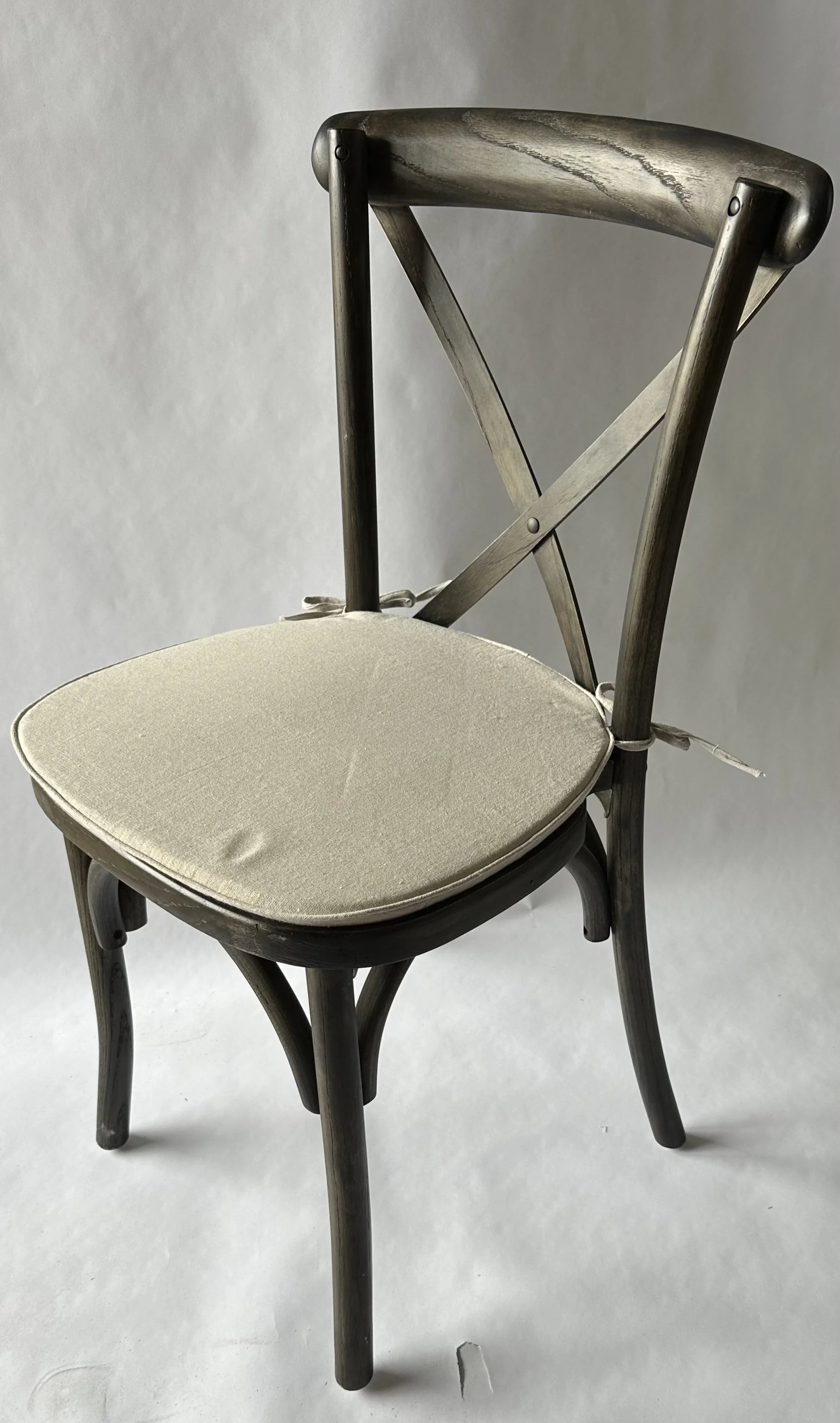 A wooden chair with a padded cushion seat and a curved backrest, set against a plain light background.